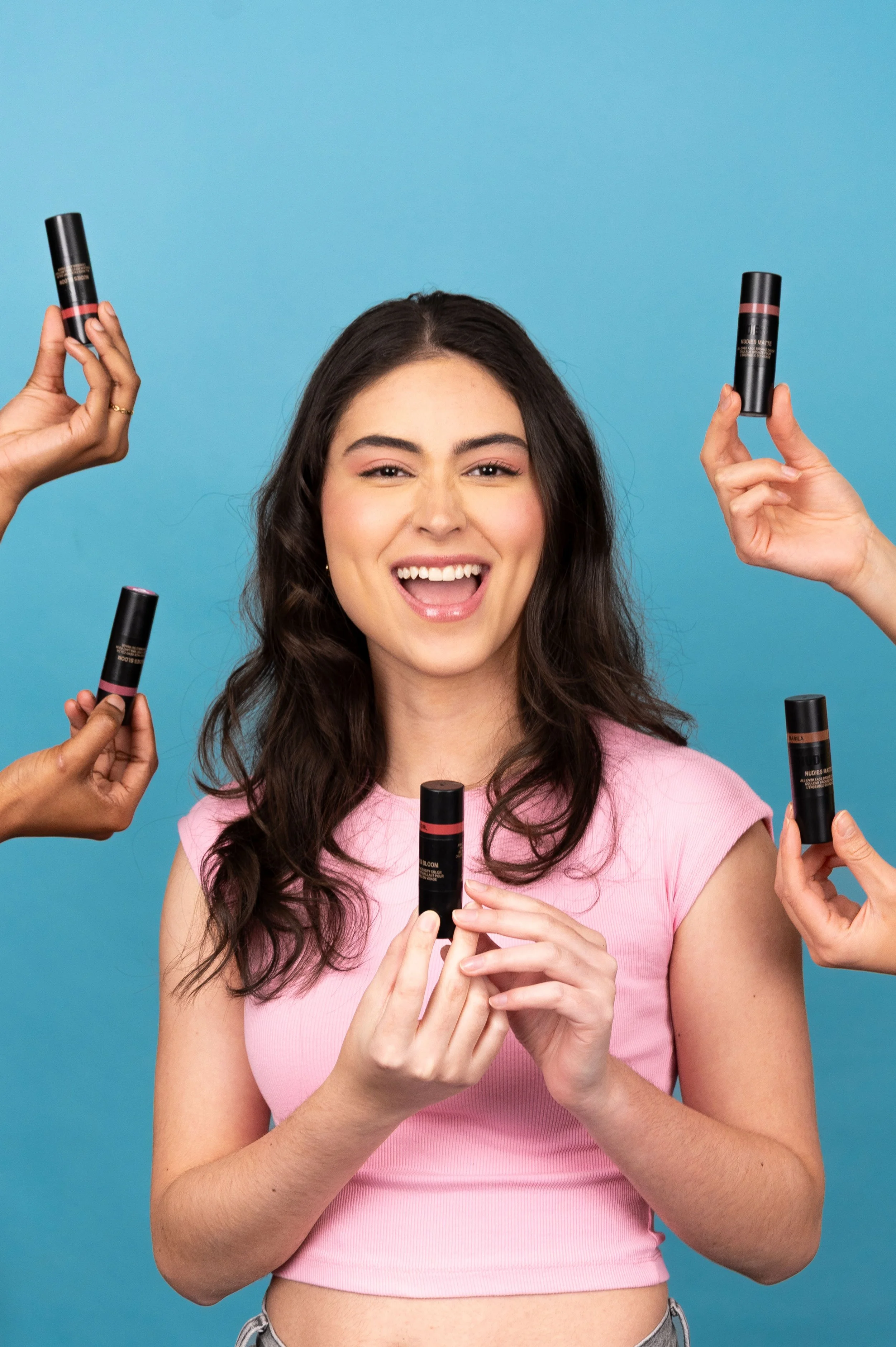 A girl in a blue background with Nudestix product