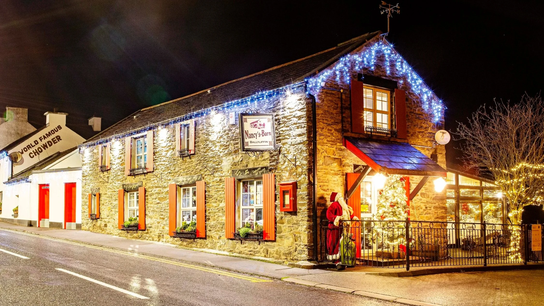 Nancy’s Barn in Ballyliffin at night, the stone building lit up with Christmas lights along the roof