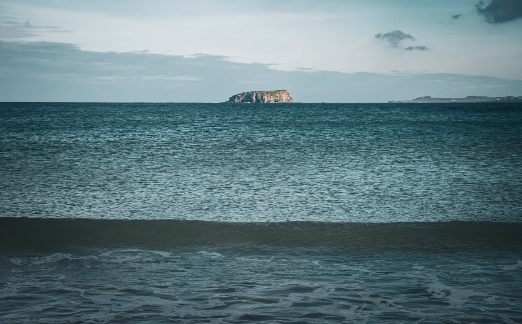 View of Glashedy island in the distance under a partly cloudy sky.