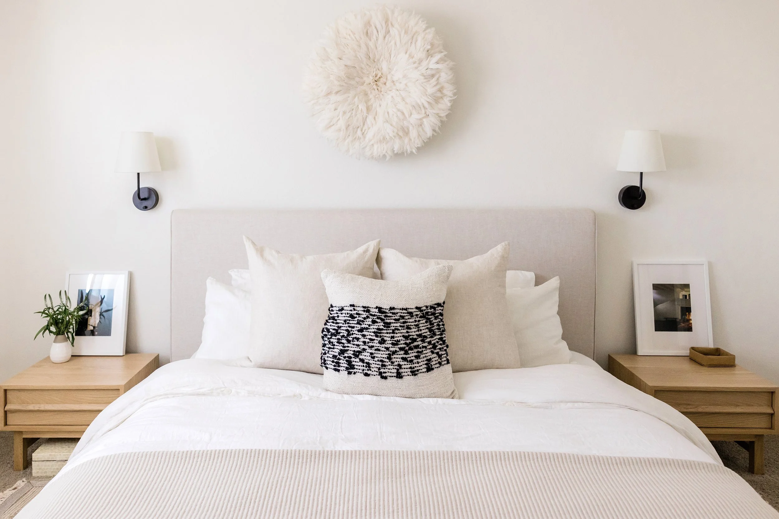 Styled primary bedroom with neutral finishes, layered bedding, and balanced lighting, representing residential interior design project support and execution.