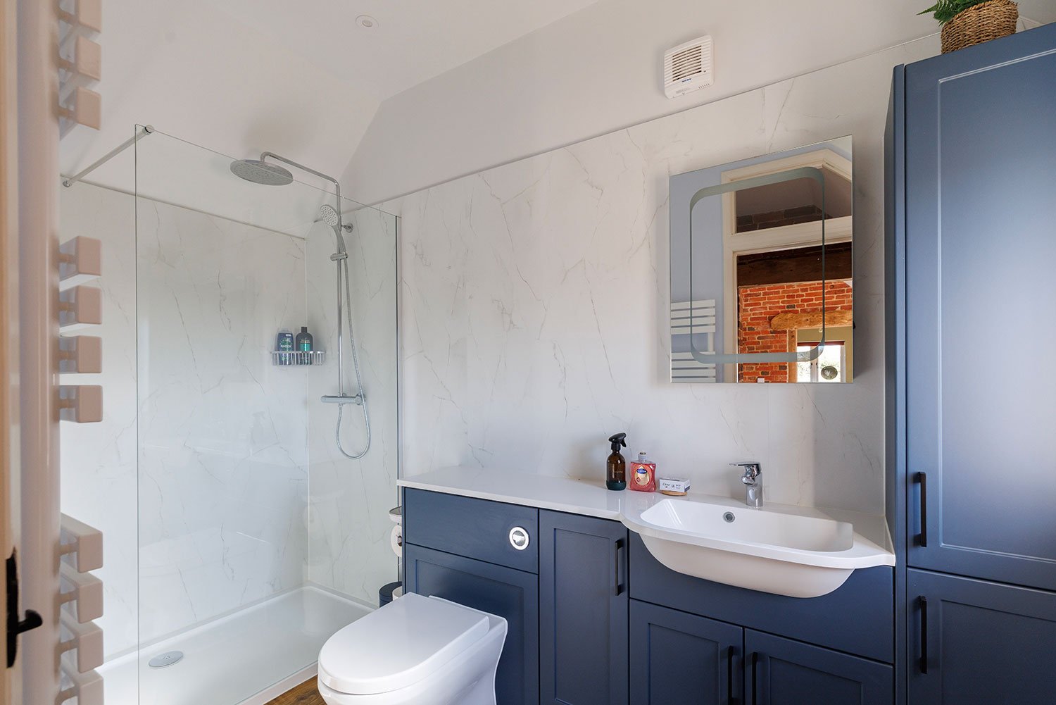 Modern shower room with heated towel rail, blue vanity and walk-in shower.