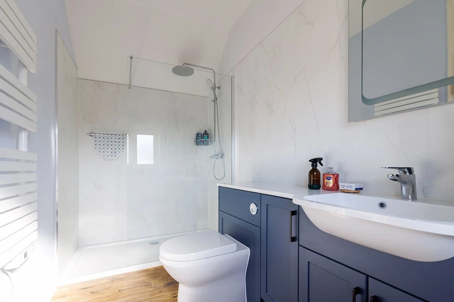 Modern shower room with rainfall shower and blue vanity.