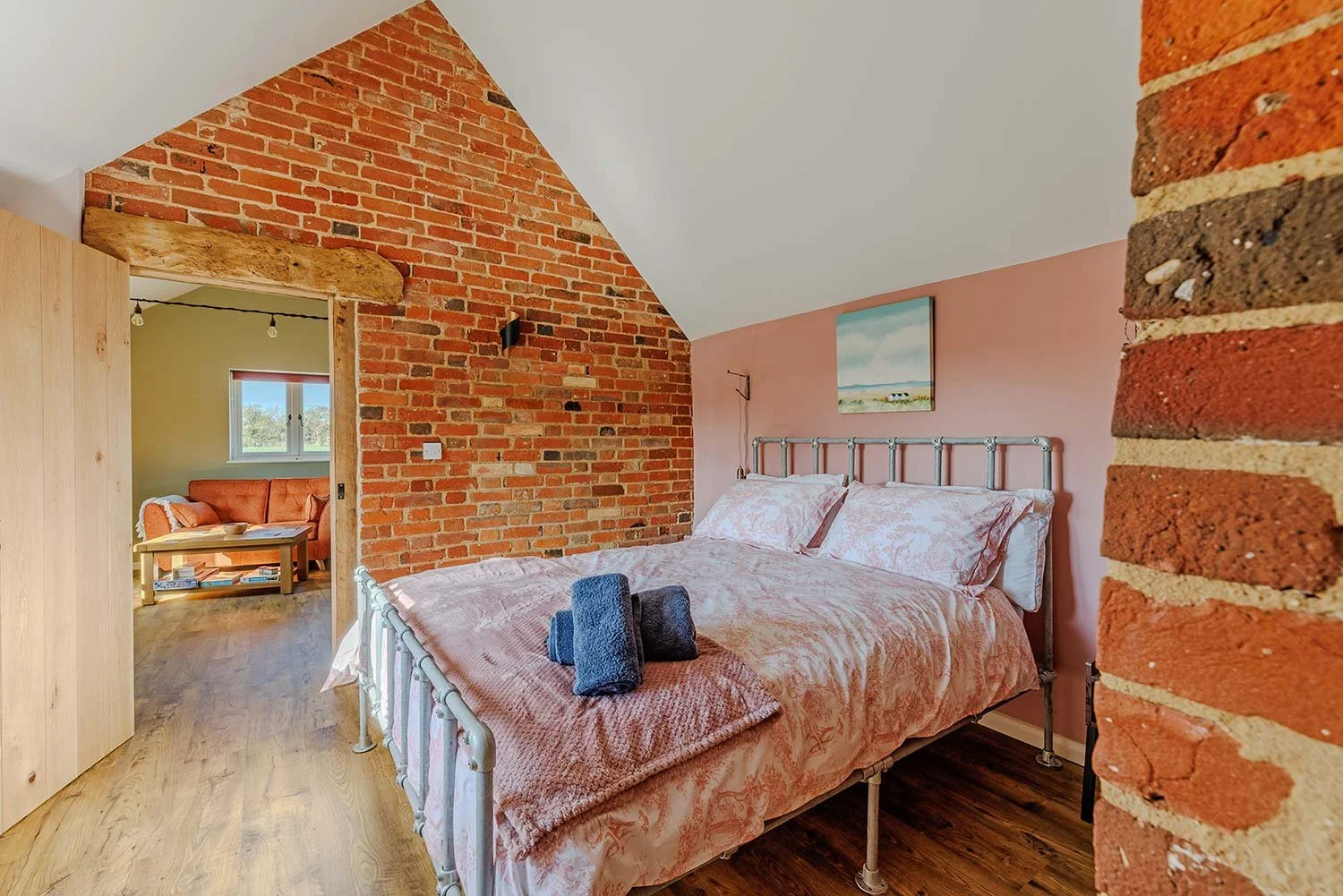 Spacious bedroom with metal bed frame and exposed brick.