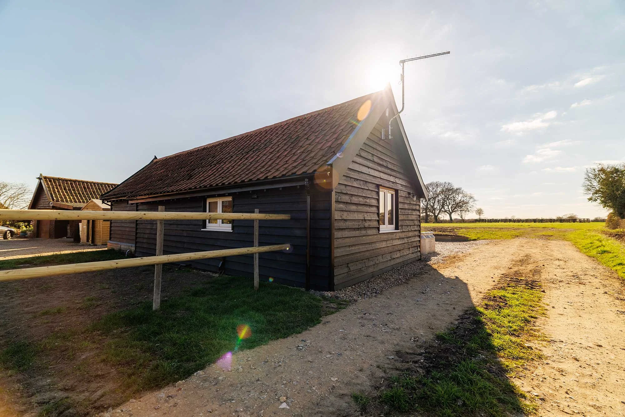 Converted black barn beside a well-marked unmade access road.