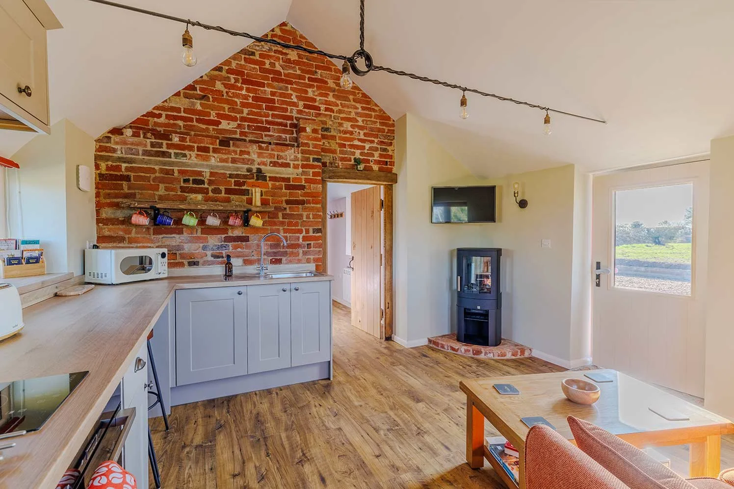 Converted barn kitchen with exposed brick and wood burner.