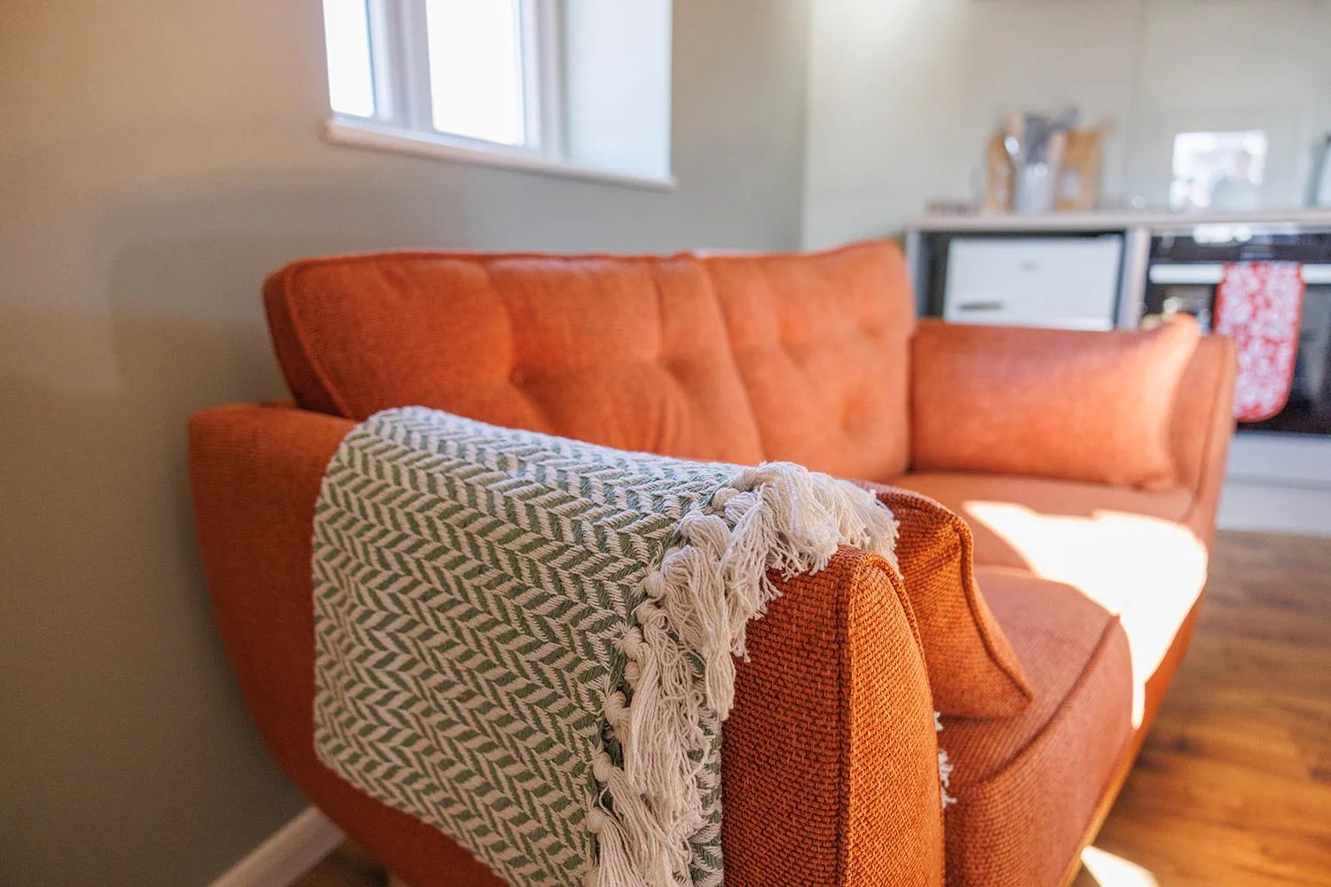 Cosy sofa with textured throw in barn living space.