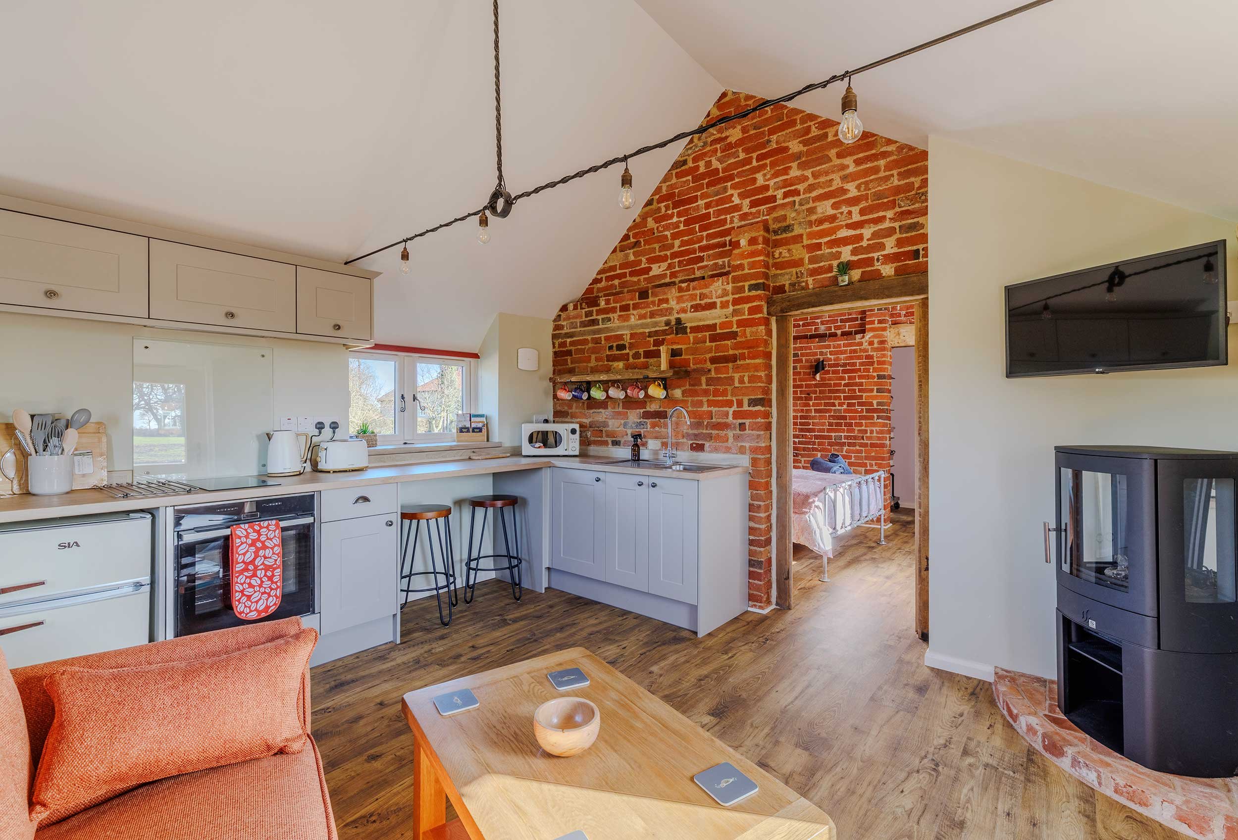 Open-plan kitchen and living area with exposed brick wall.
