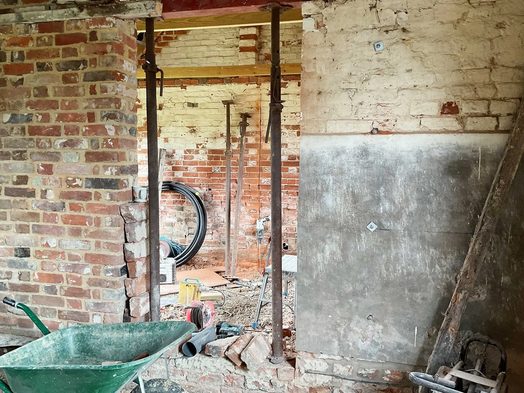 Barn interior during renovation with exposed brick and supports.