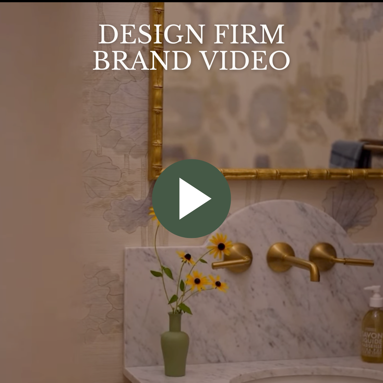 bathroom sink with a marble countertop, gold-colored faucet, and a small green vase with yellow flowers. Behind the sink, there is a decorative mirror with a bamboo-style frame and a wall with floral and map patterns. Overlaid text reads 'Design Firm