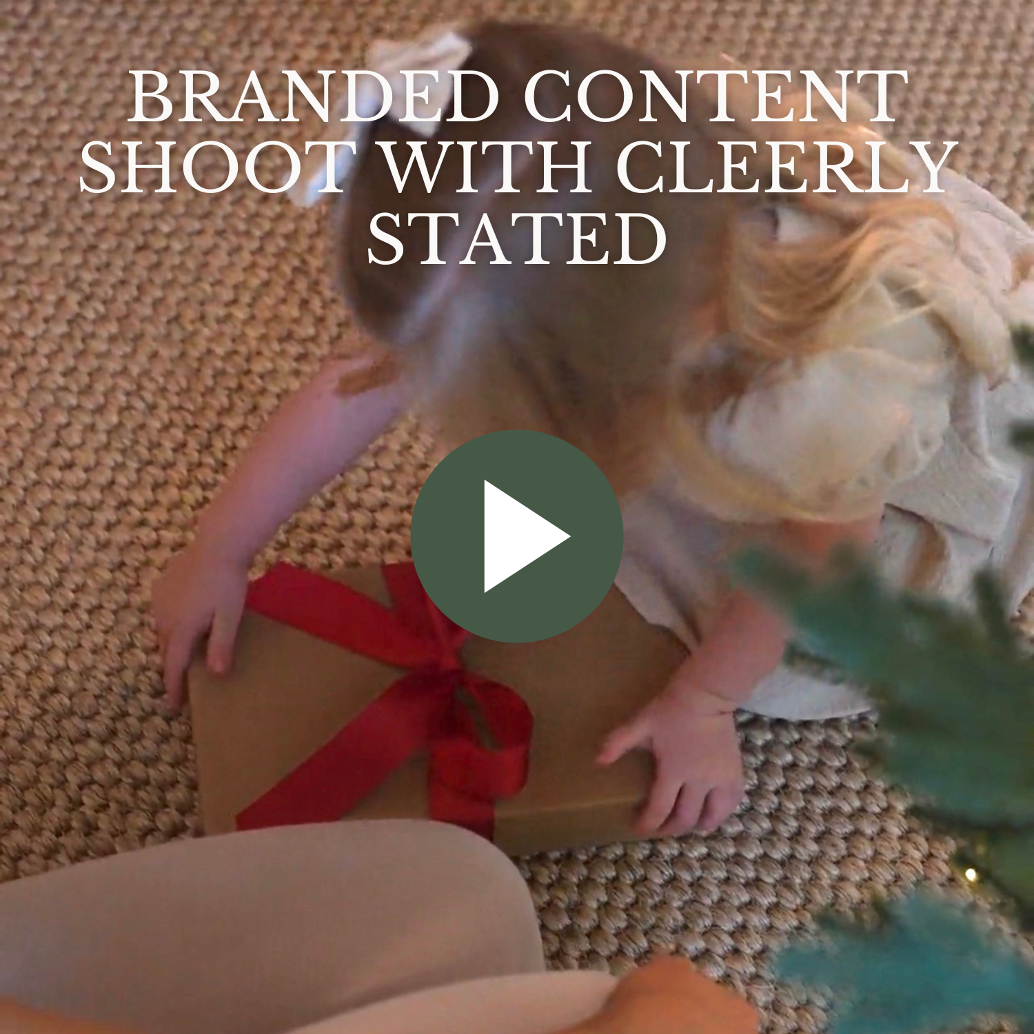 Child holding a gift with a red ribbon on a carpeted floor