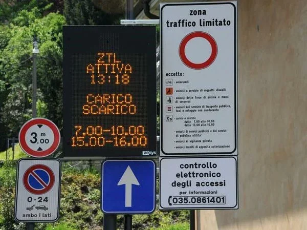 Road signs indicating restricted traffic zone, electronic sign about traffic regulation, and directions for vehicles.