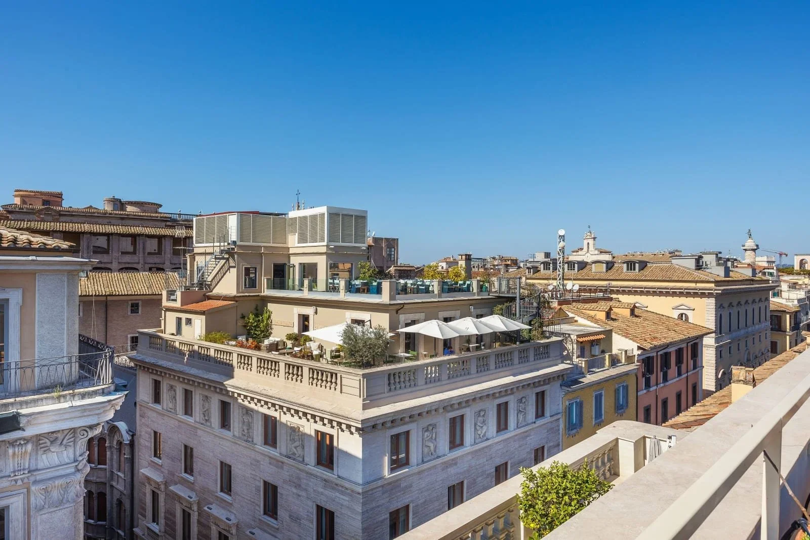Cityscape view of rooftop terraces and historic European-style buildings under a clear blue sky.