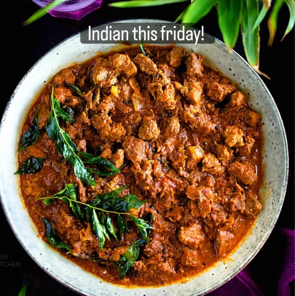 A bowl of Indian curry garnished with fresh green curry leaves, served in a white bowl on a black surface with purple and green decorative elements around.