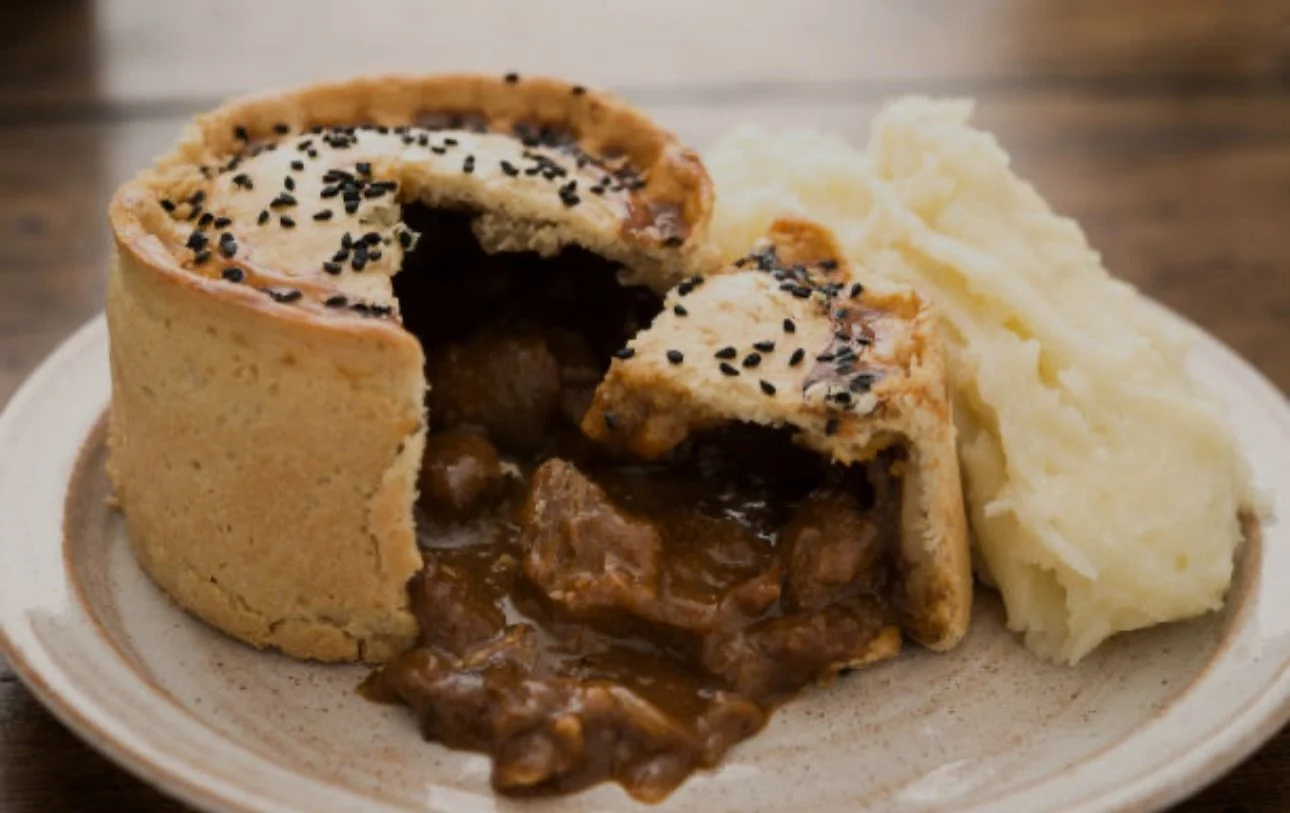 Meat pie served with mashed potatoes on a ceramic plate.