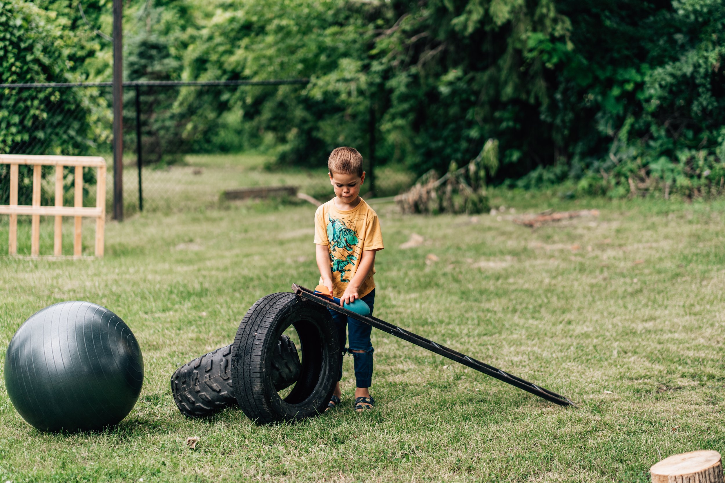 Boy building a race track with a metal frame and tires at the Belleville Outdoor Preschool