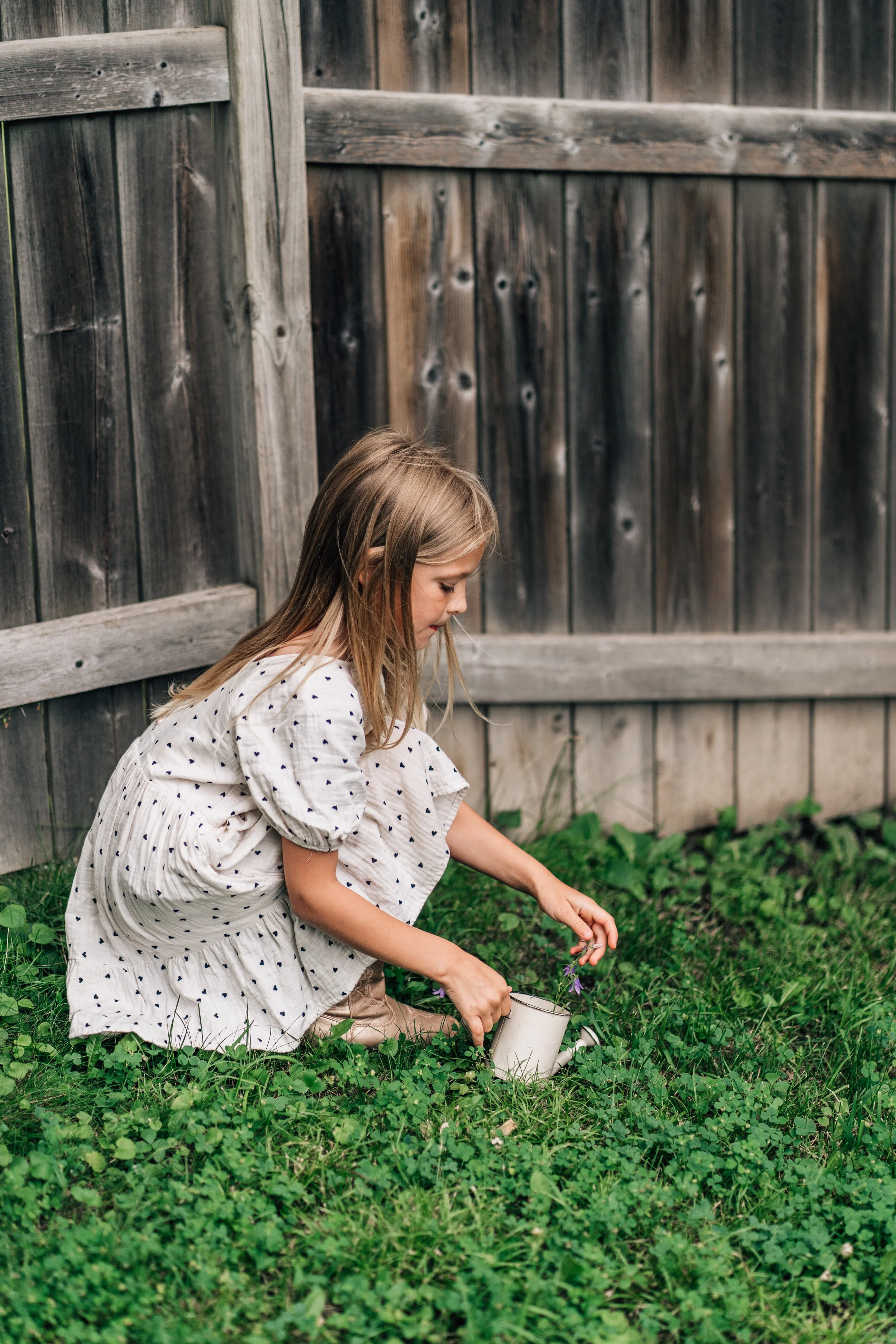 Girl in white dress picking flowers at the Belleville Outdoor Preschool