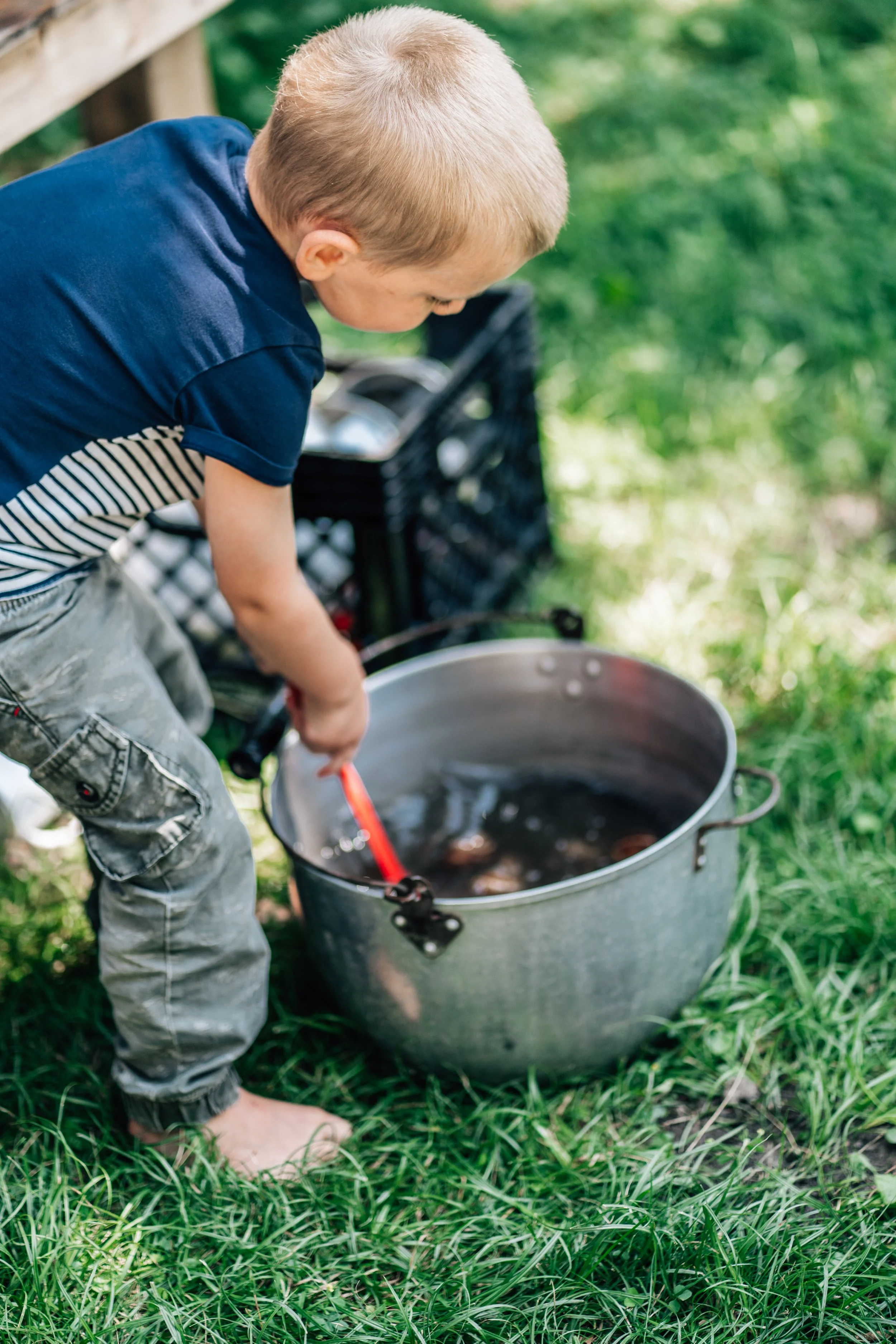 Boy stirring a nature soup at the Belleville Outdoor Preschool