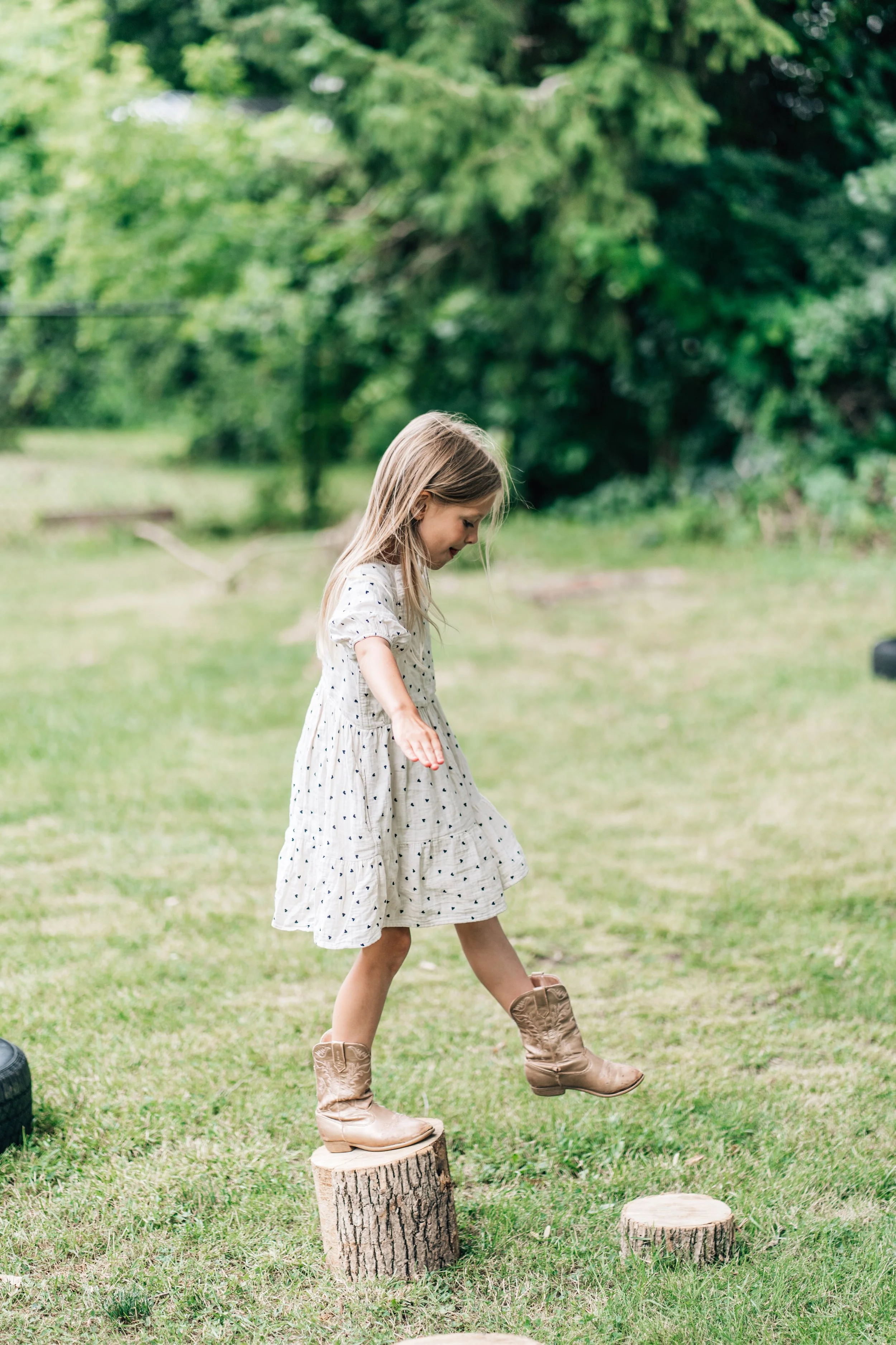 Girl jumping from one log to the next at at the Belleville Outdoor Preschool