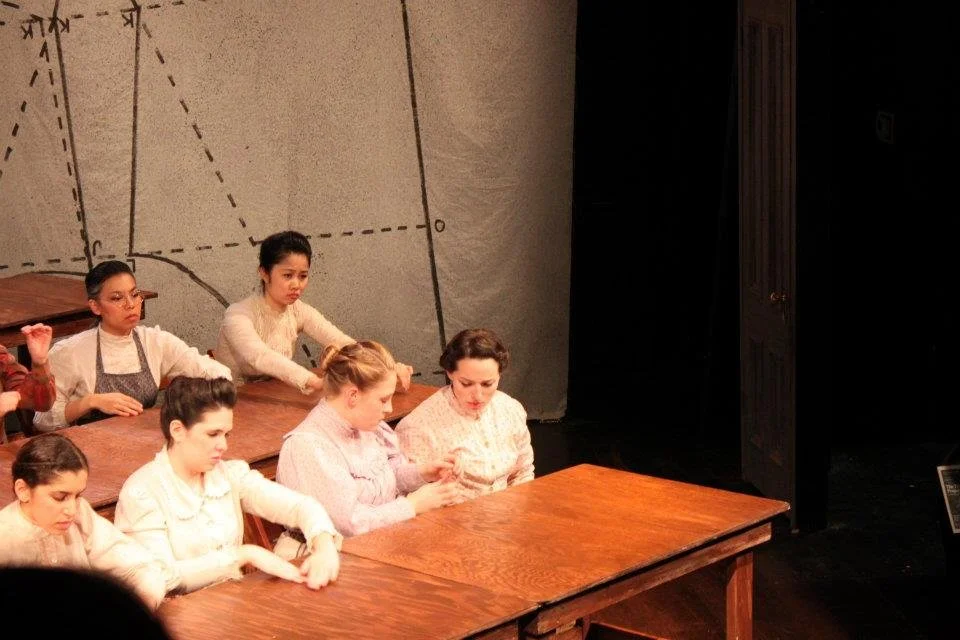 The image shows a group of young women sitting at wooden desks in a classroom setting, with a diagram of geometric shapes and lines on the blackboard behind them.