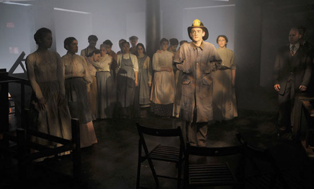 A group of mannequins depicting a historical scene, including a firefighter in uniform holding a clipboard, in a dimly lit room.