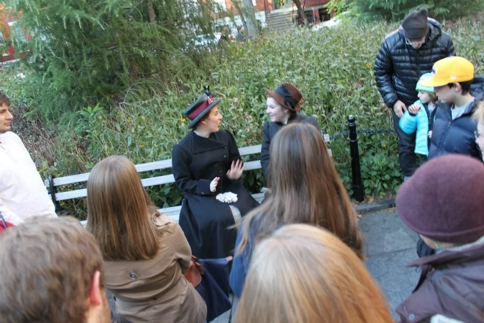 Costumed actors performing a historical reenactment for a small outdoor audience in a park.