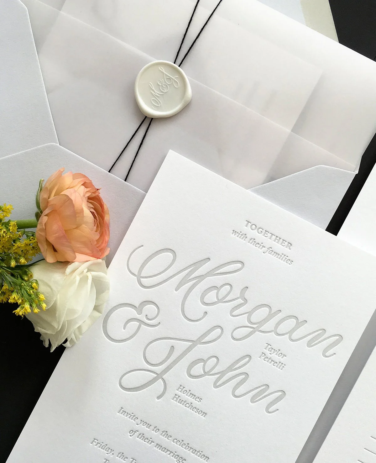 Wedding invitation for Morgan and John with floral decoration and a sealed envelope with a wax seal.