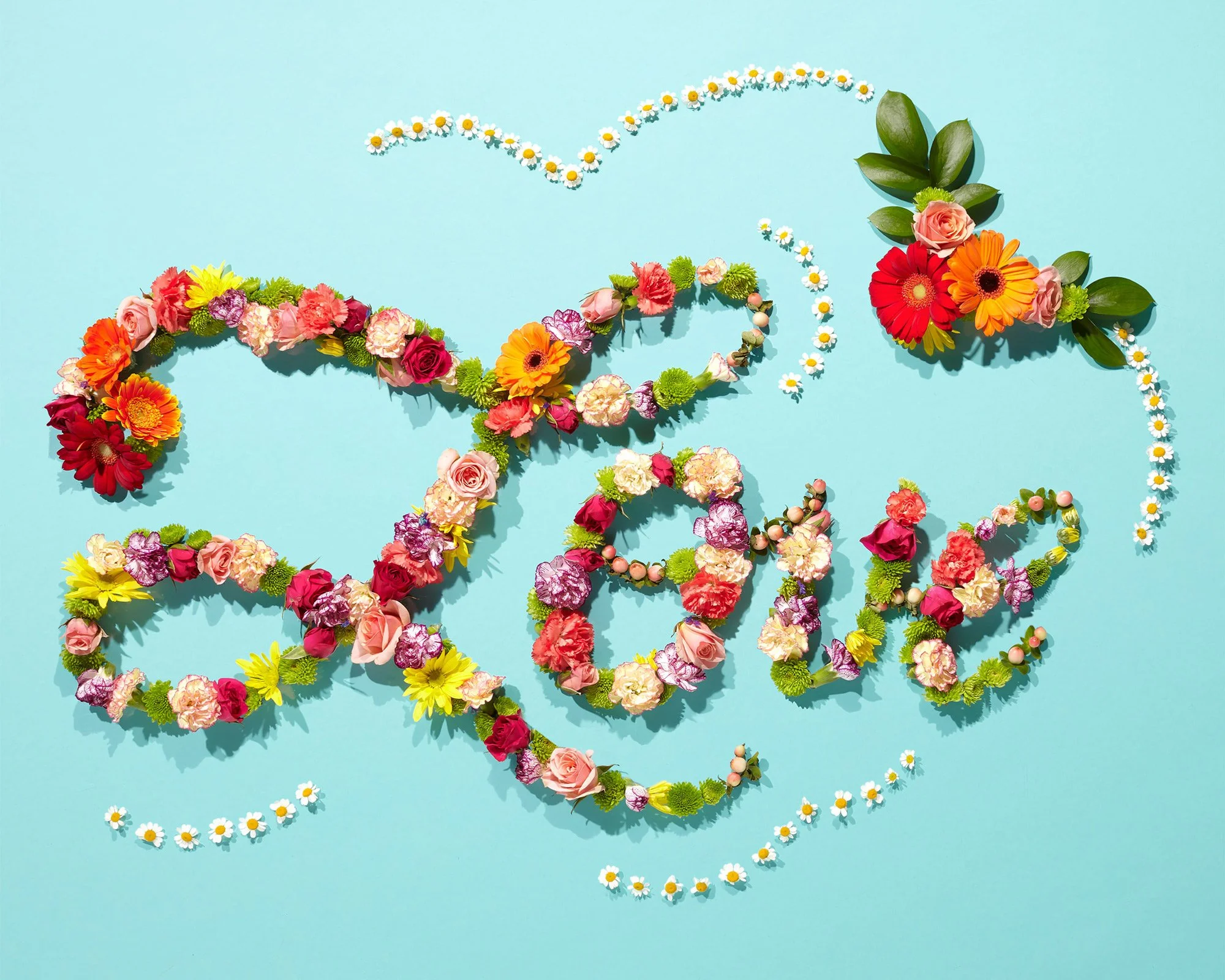 The word "LOVE" written with various colorful flowers on a blue background, with flower decorations surrounding the word.