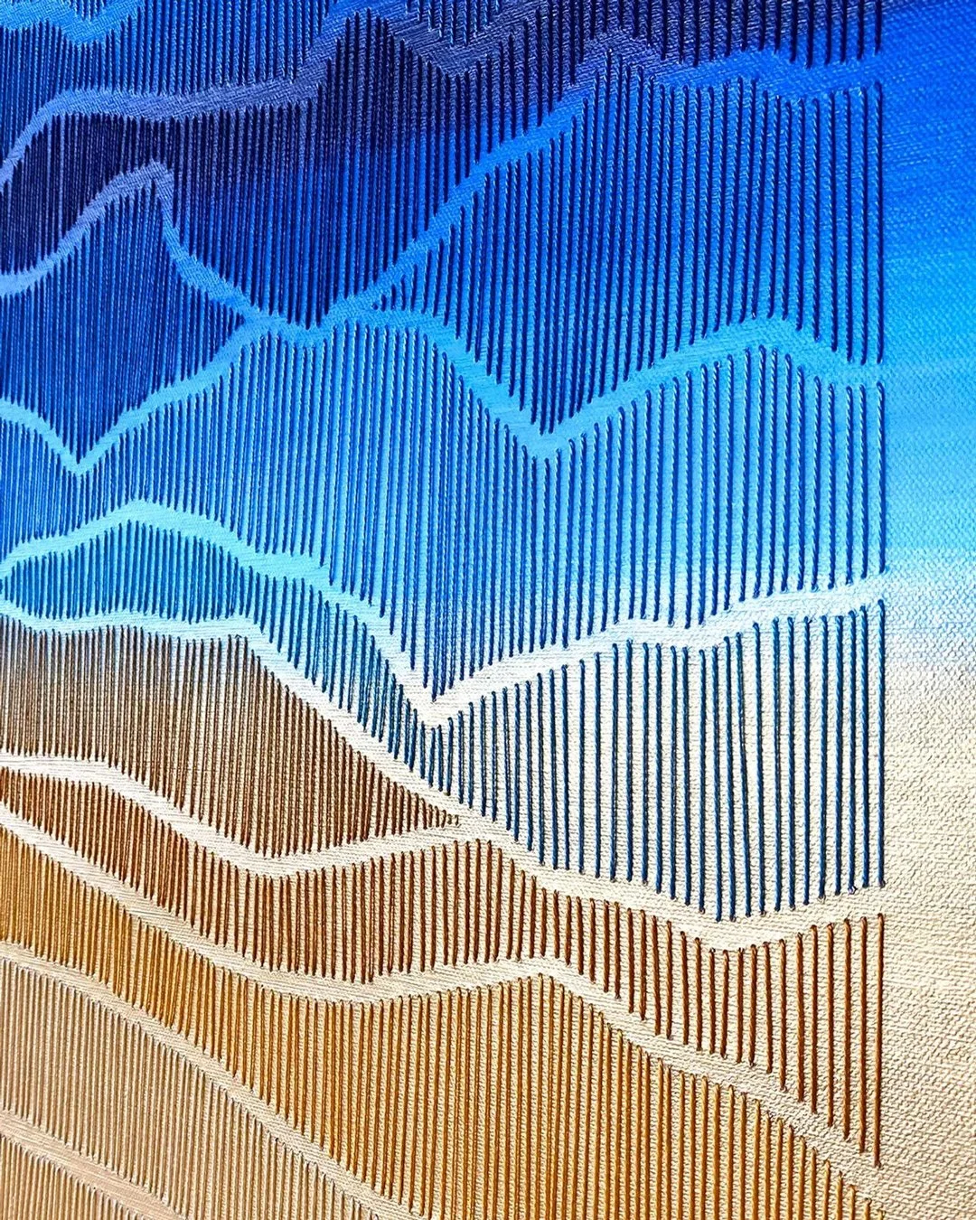 Close-up photograph of a textured, geometric pattern with wavy lines in shades of brown, blue, and white.