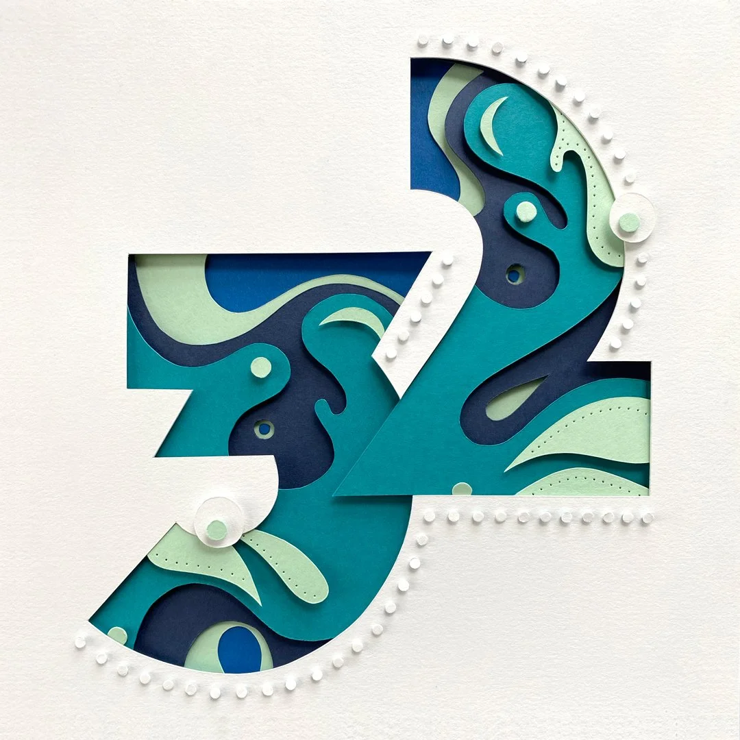 Pop-up greeting card with layered blue and green abstract patterns and the number 52 cut out of the paper.