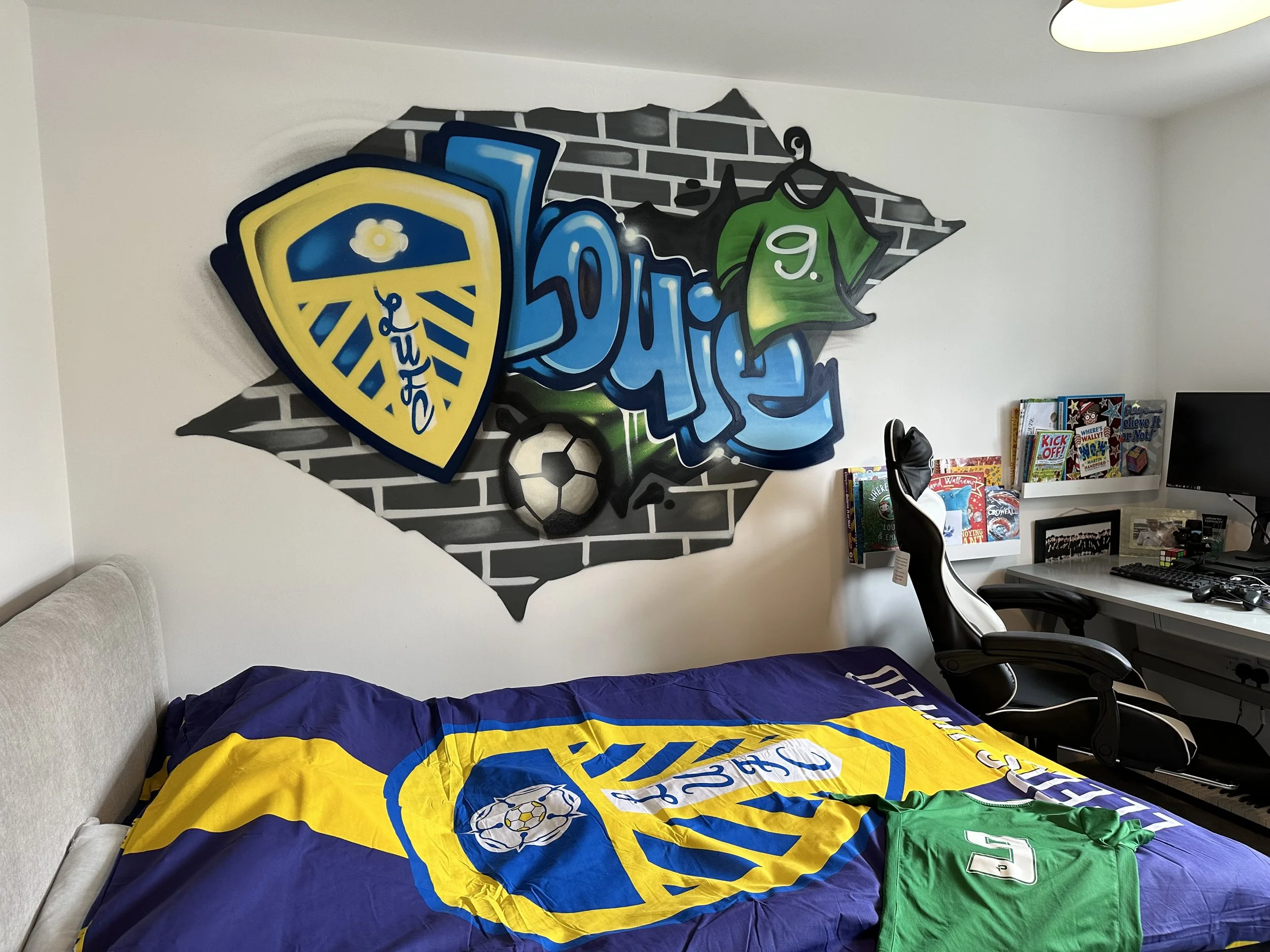 A bedroom with a soccer-themed decor, featuring a Bryant soccer team banner on the bedspread, a green sports jersey with the number 9, and a graffiti-style wall art of a soccer shield, jersey, and soccer ball.