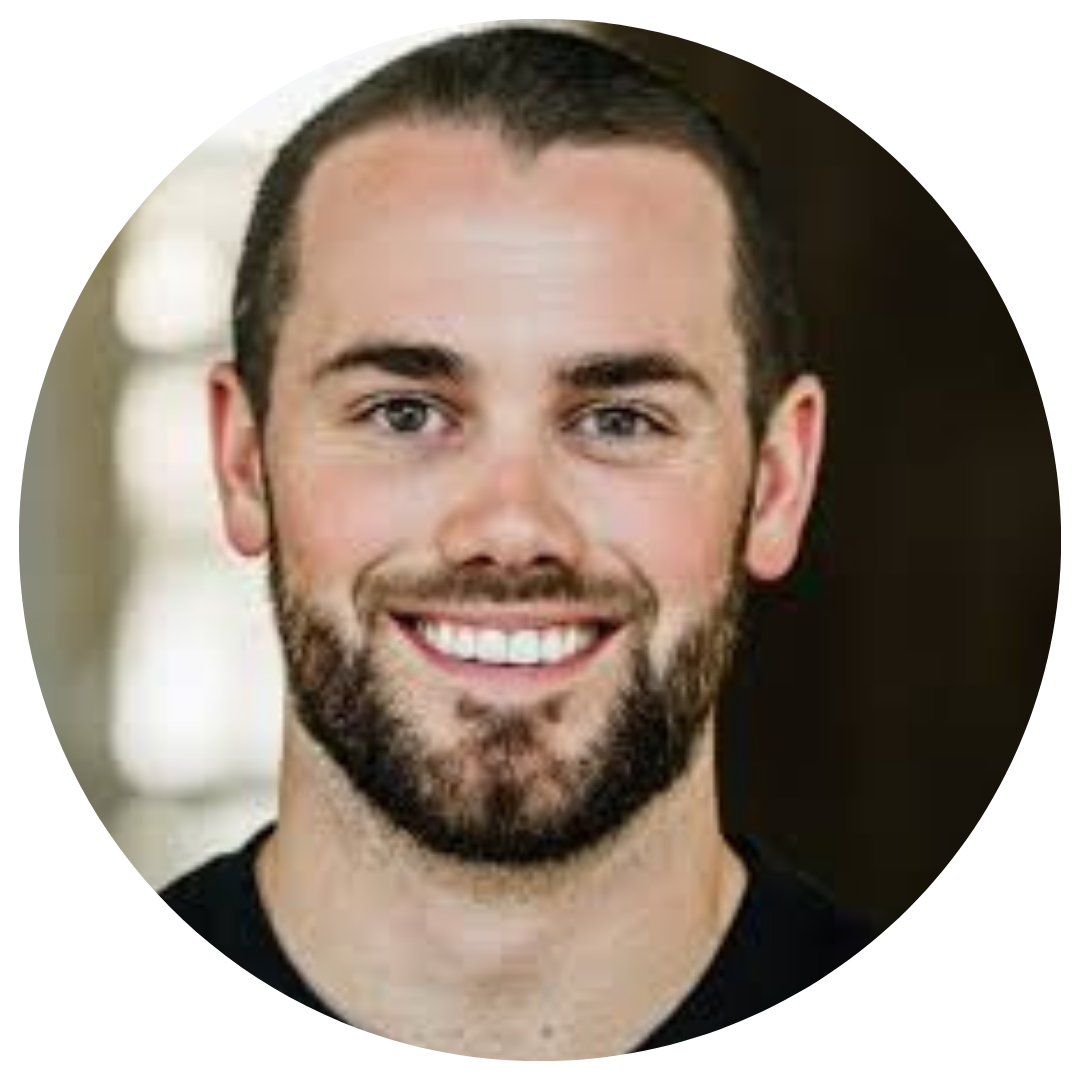 Close-up of a smiling man with short dark hair and a beard, wearing a black shirt.