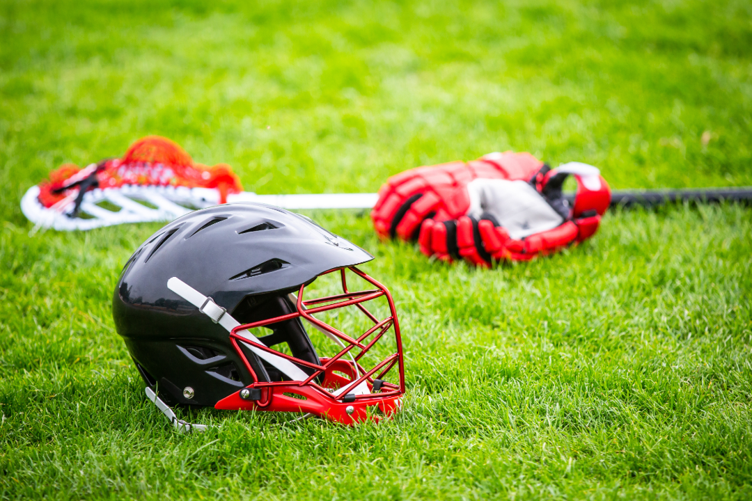 Lacrosse helmet, stick, and gloves on the green grass