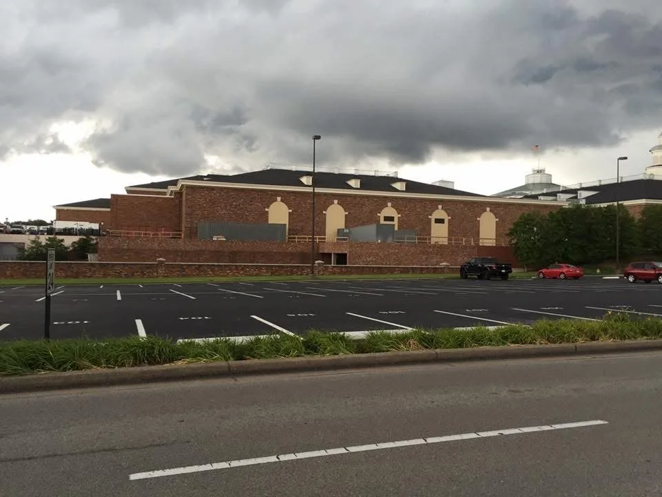 Empty parking lot in front of a large brick building under a cloudy sky.