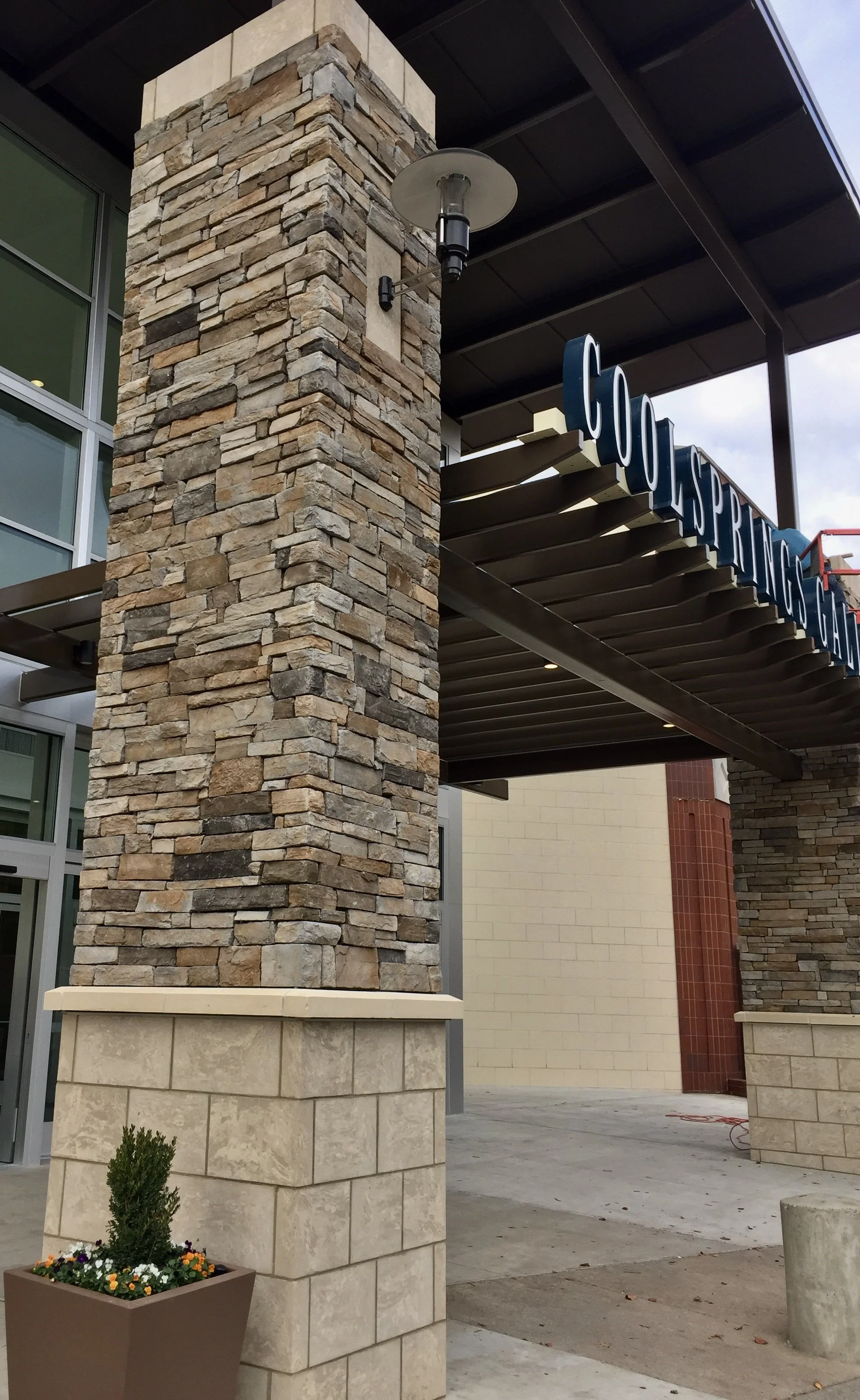 Exterior of a building with stone and brick columns, under an awning with a sign that reads 'Cool Springs'.
