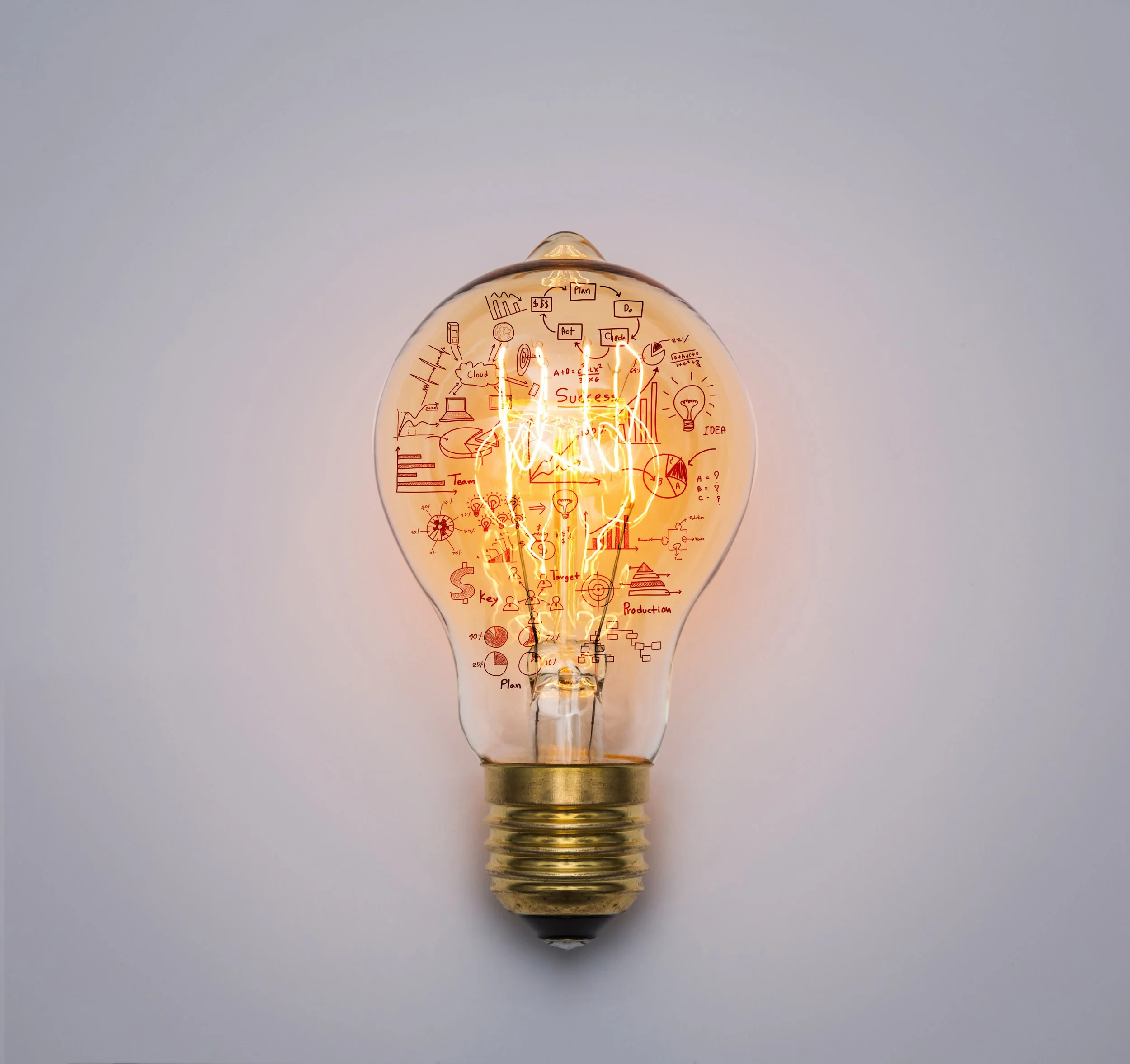 Illuminated light bulb with red sketches and notes about ideas, success, and planning inside