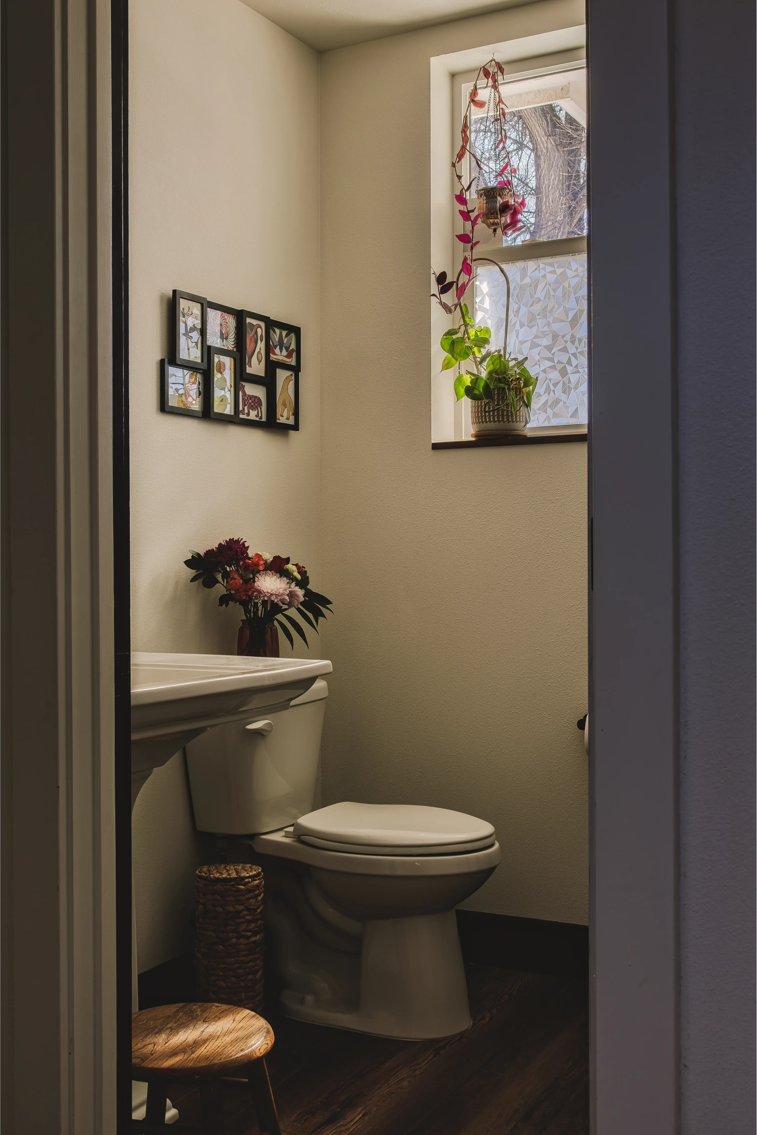 A small bathroom with a white toilet, a white sink, and framed animal art on the wall, shot in Berthoud, Colorado by Context Images.