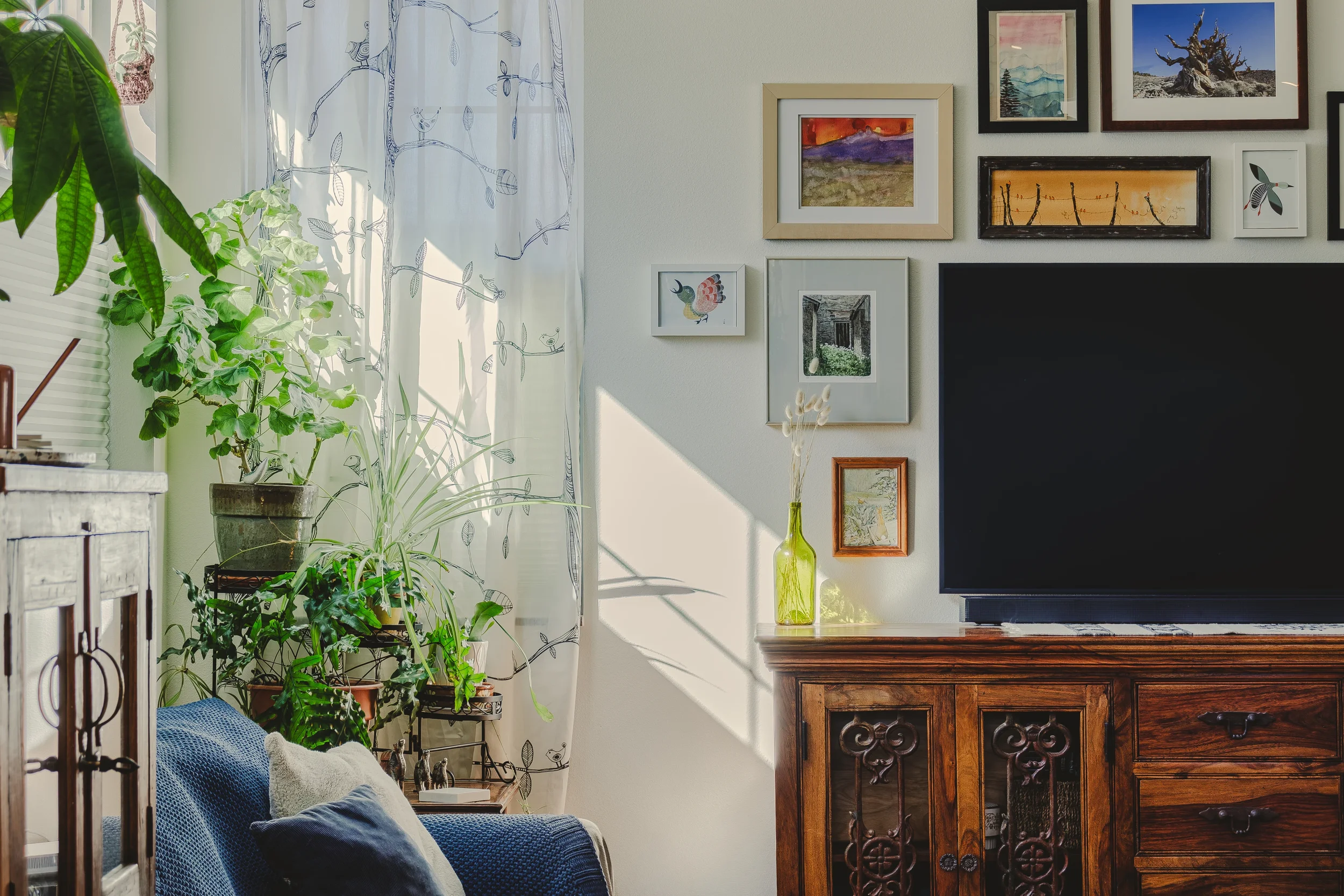 Living room corner with a dark wooden cabinet and wall adorned with various framed art, shot in Berthoud, Colorado.