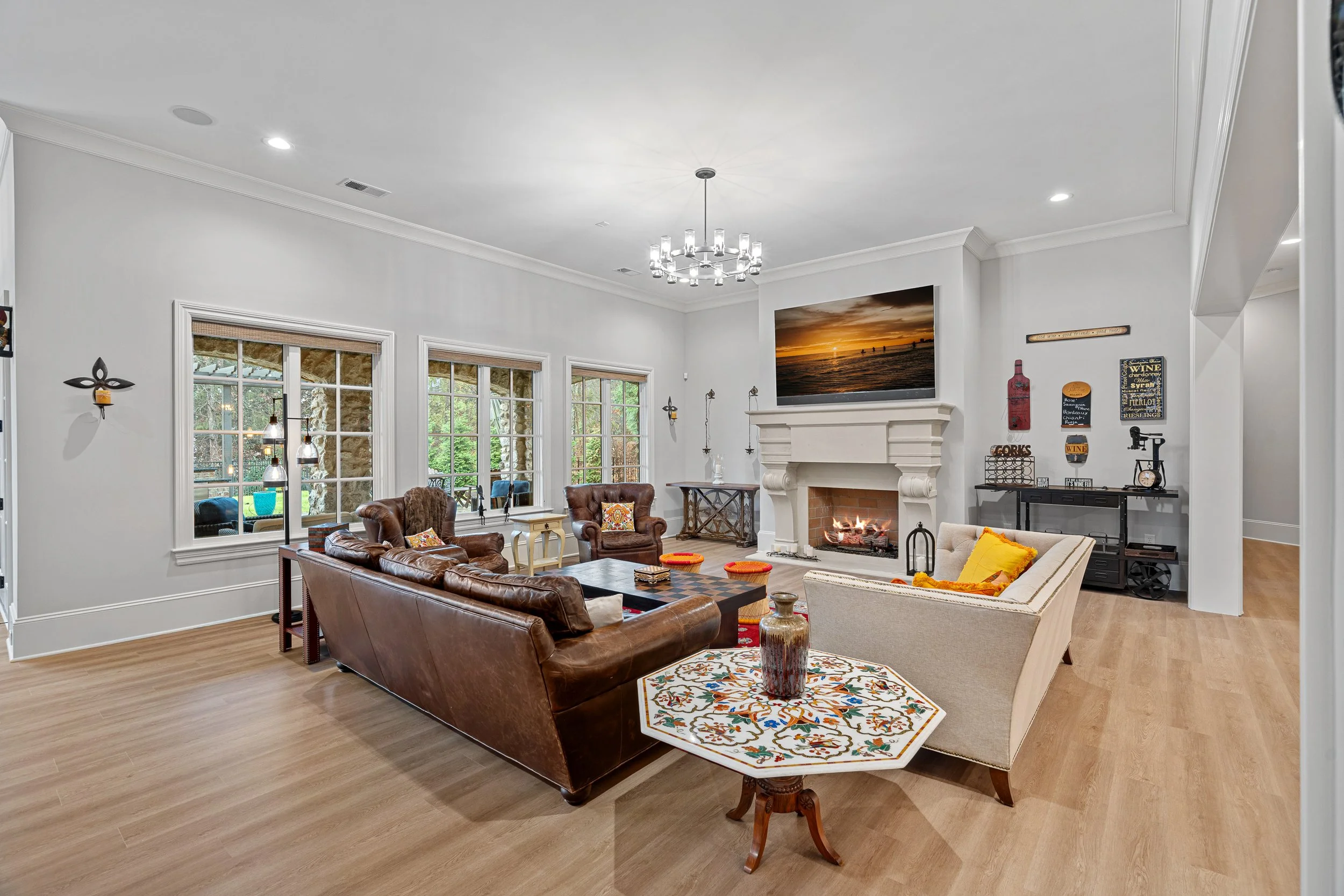Living room with leather sofas, a fireplace, wall-mounted television, windows, and decorations.