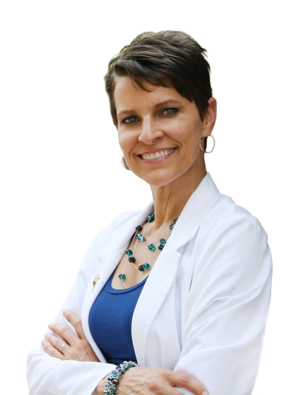 A smiling woman with short dark hair, light skin, wearing a white coat, blue top, and jewelry, standing with arms crossed.