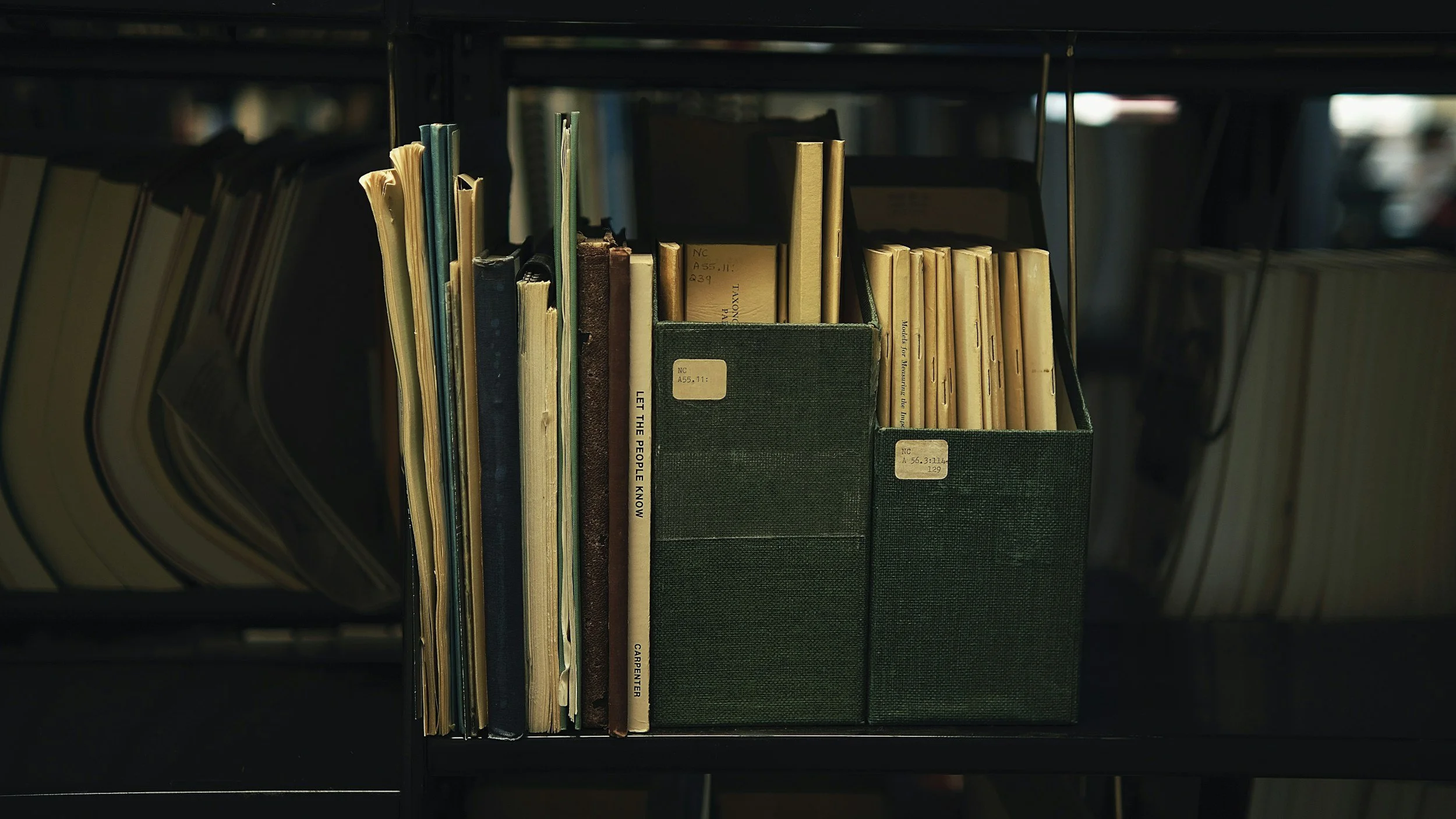 Books and binders on a library shelf.