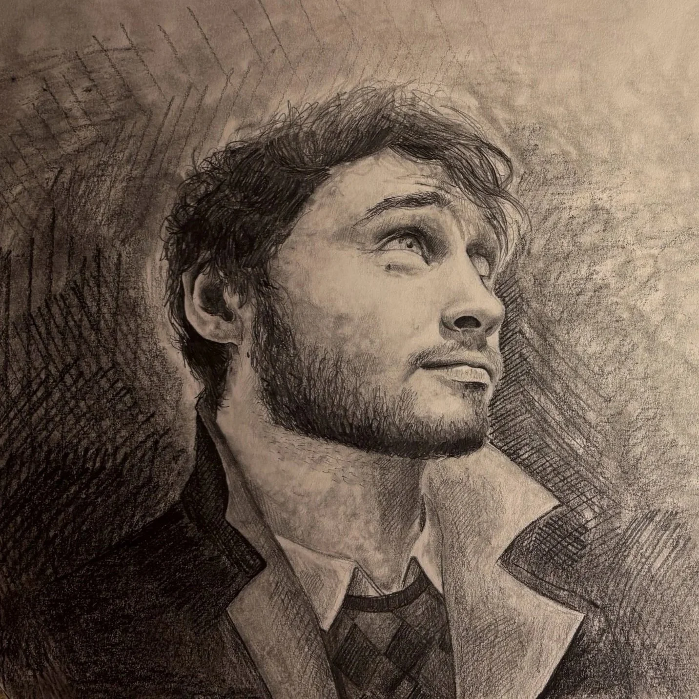 Sketch of a young man with a beard and tousled hair, looking upward with a confident expression, wearing a jacket and tie.