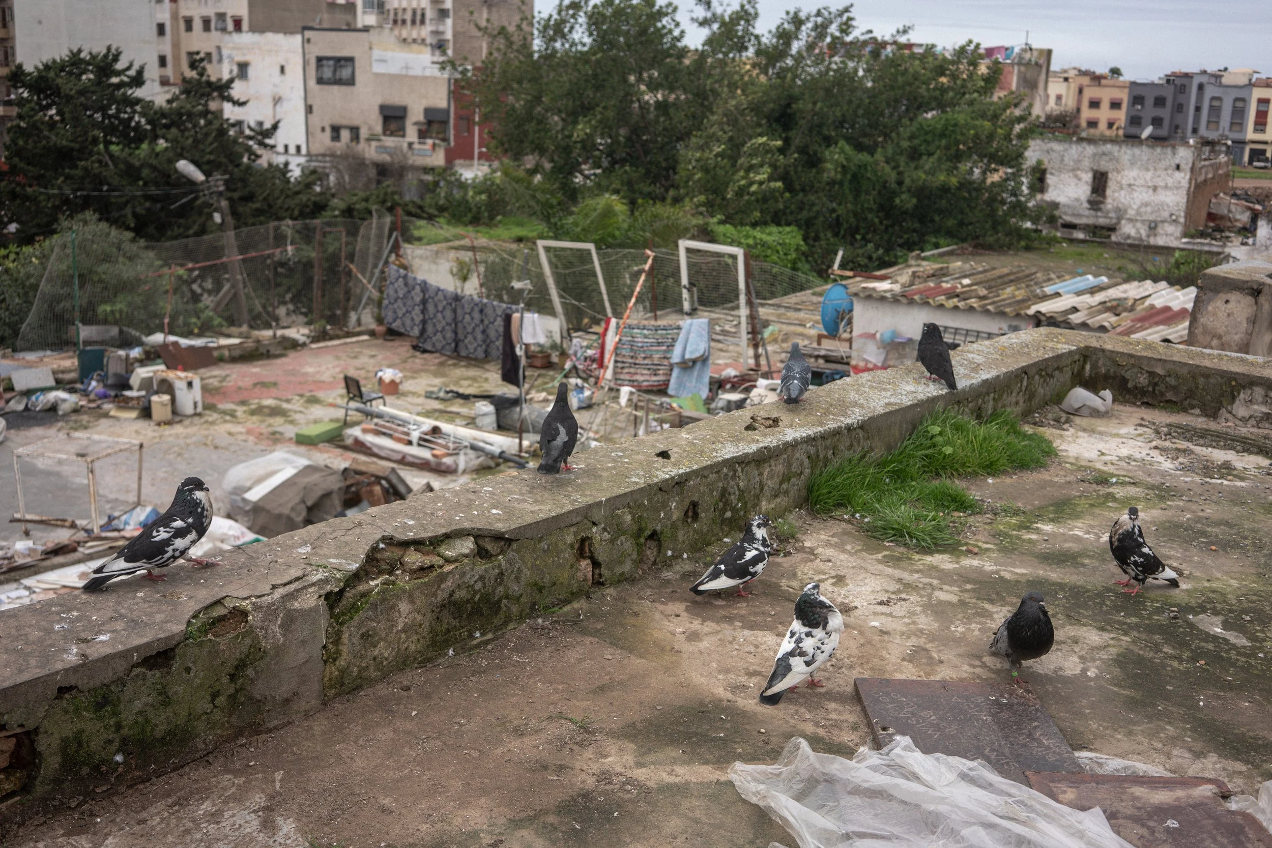 On the roof above deteriorating rooms, life continues in the open air. Among cracked walls and drying laundry, wind moves freely across a space left unprotected from the weather.
