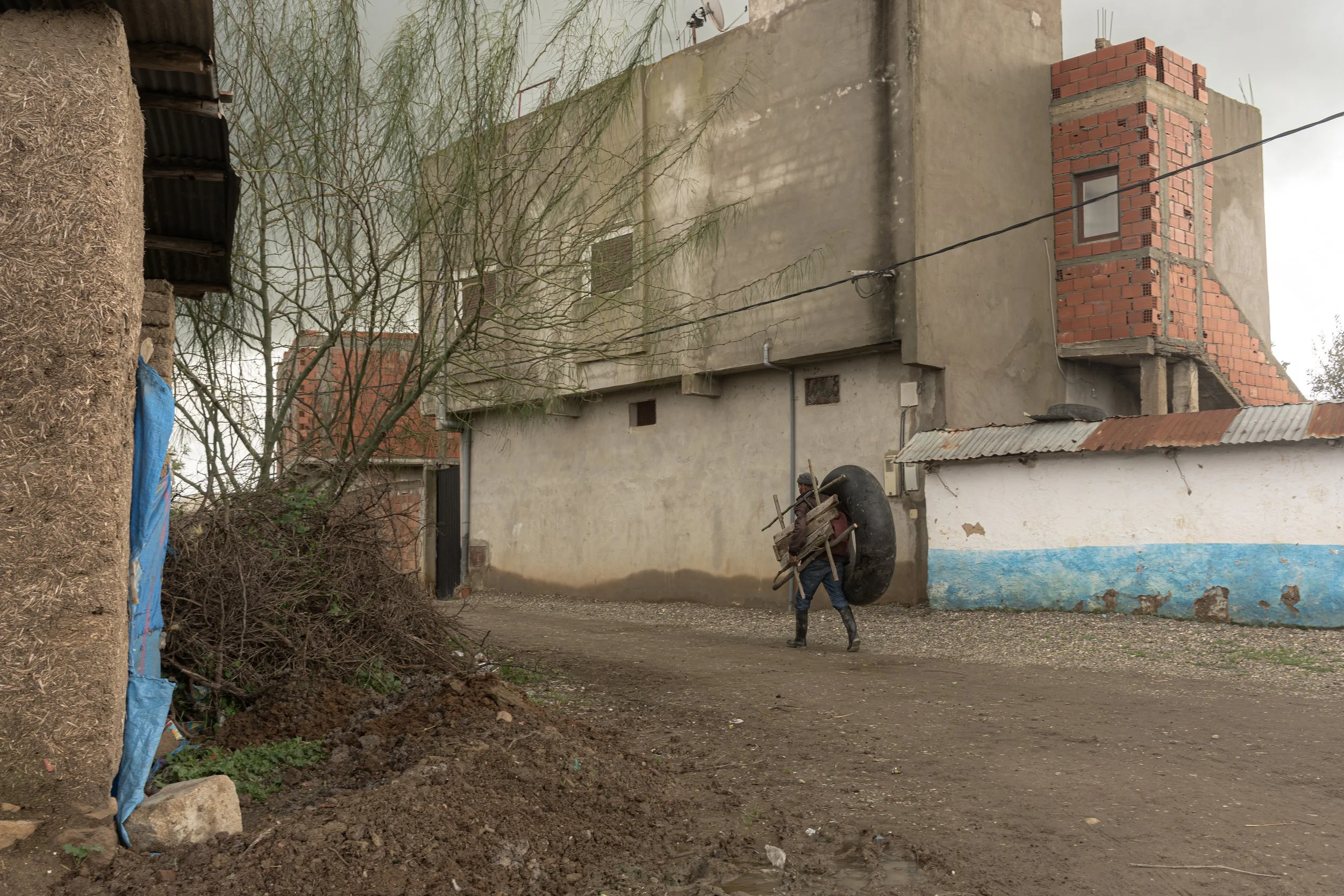 Adaptations forged by necessity. Equipped with an inflated inner tube and essential furniture, a villager moves down the quiet alley, turning everyday materials into vital tools to navigate the water.