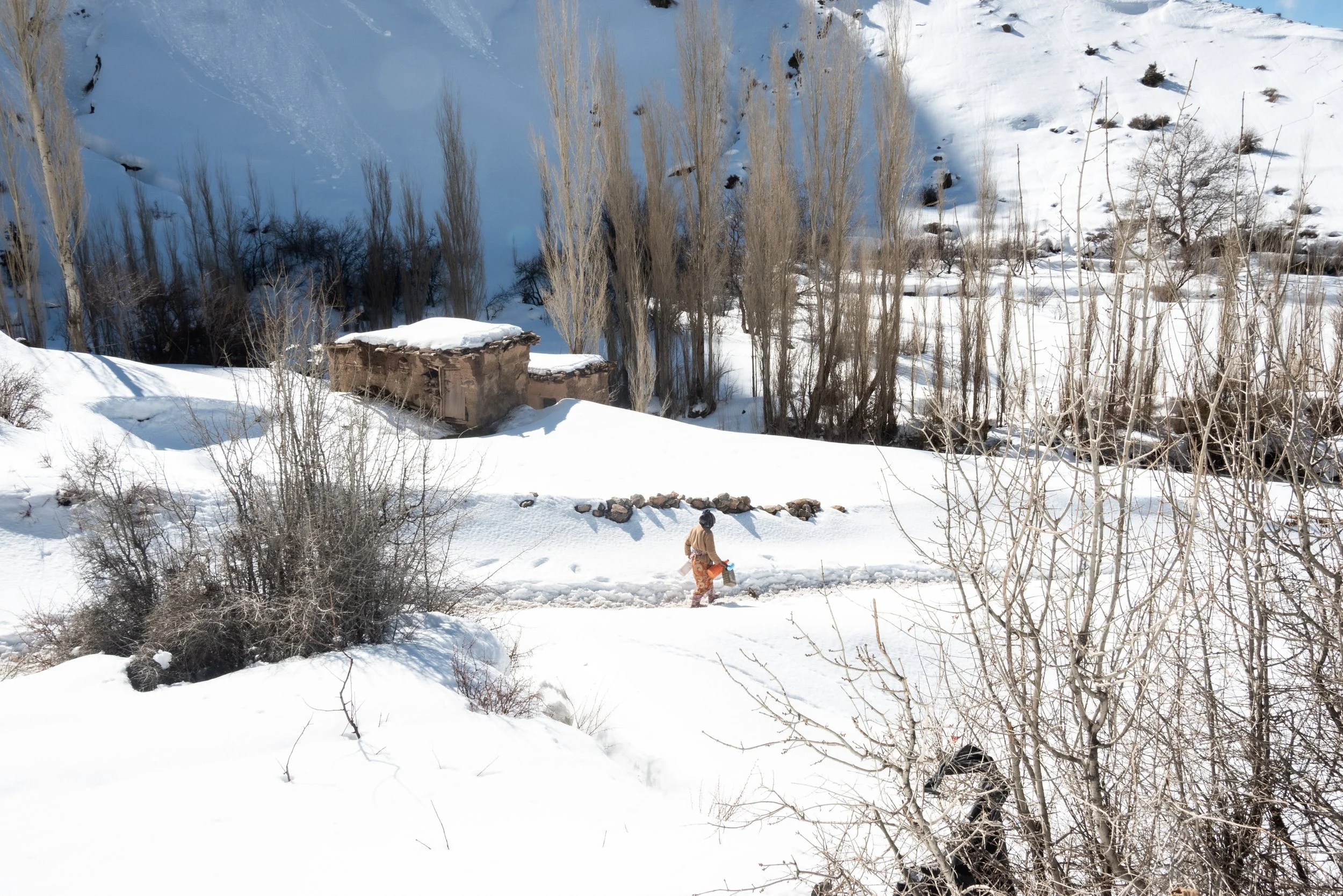 Daily life carries on through the snowbound valley, where traditional earthen architecture and cold mountain trails frame the quiet rhythms of the village.