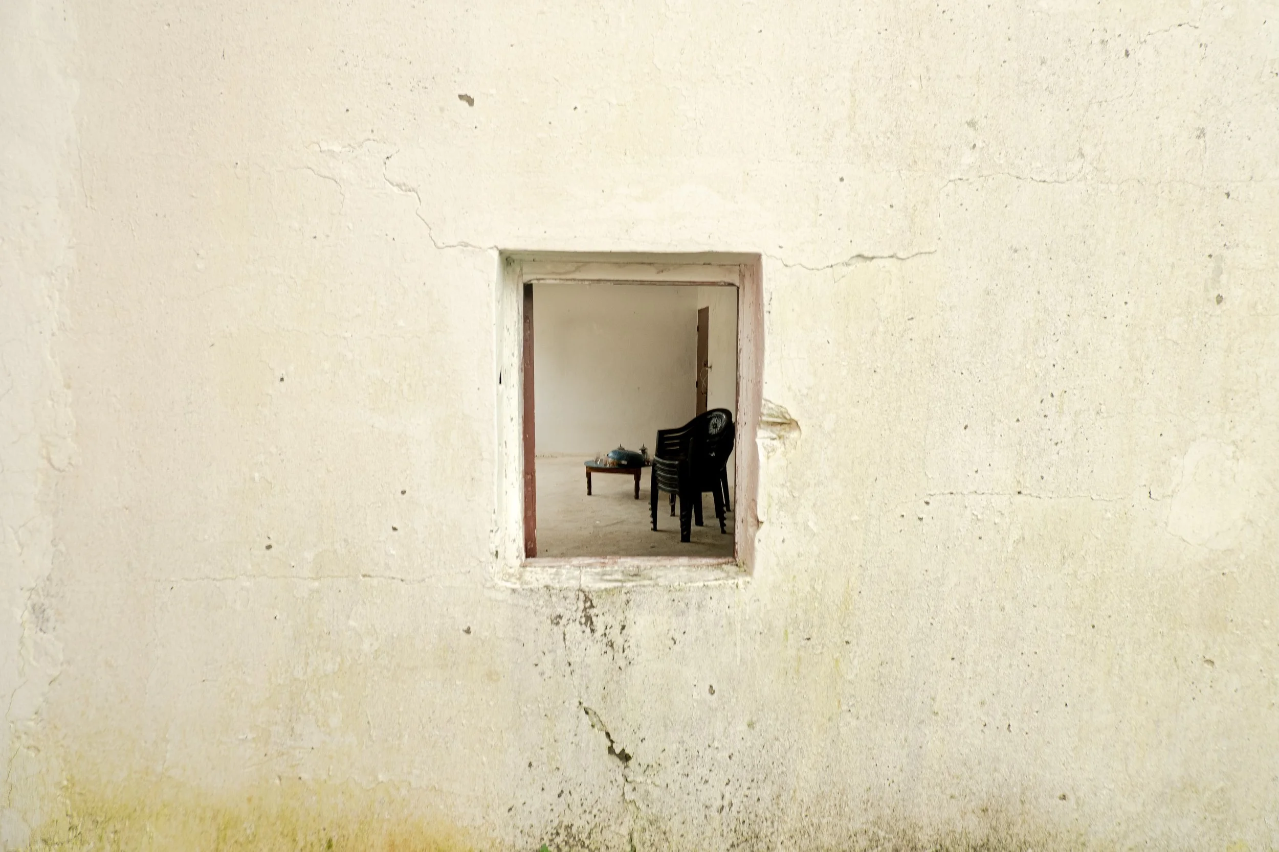 Looking inside a home brought down to its simplest form. The chairs and small tea table remain gathered together, holding space for daily life to resume once the water recedes.