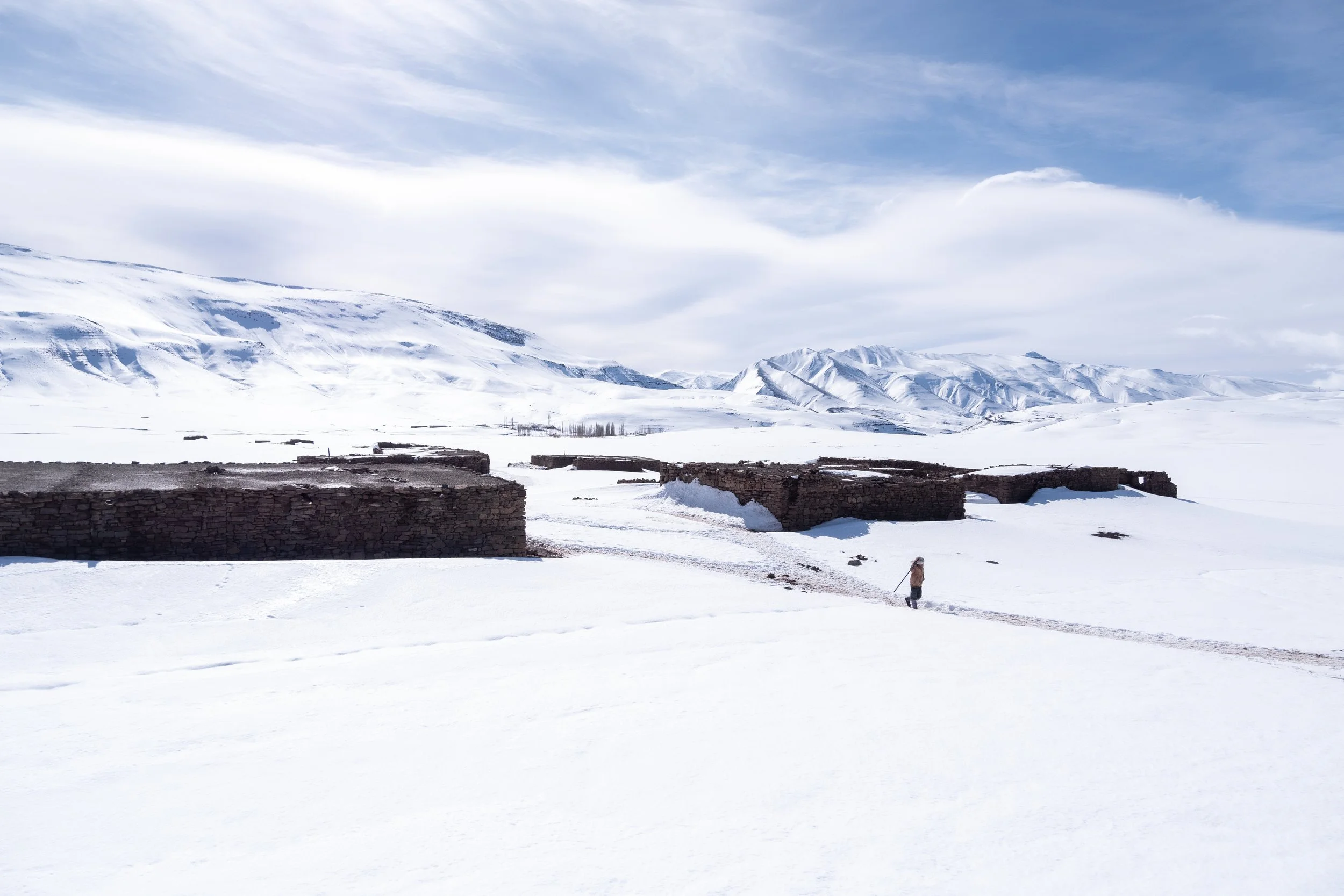 A heavy blanket of winter snow nearly swallows the low stone walls of a remote mountain settlement near Imilchil. When severe winter storms strike this high-altitude region, rudimentary roads and paths are instantly buried under deep drifts, severing
