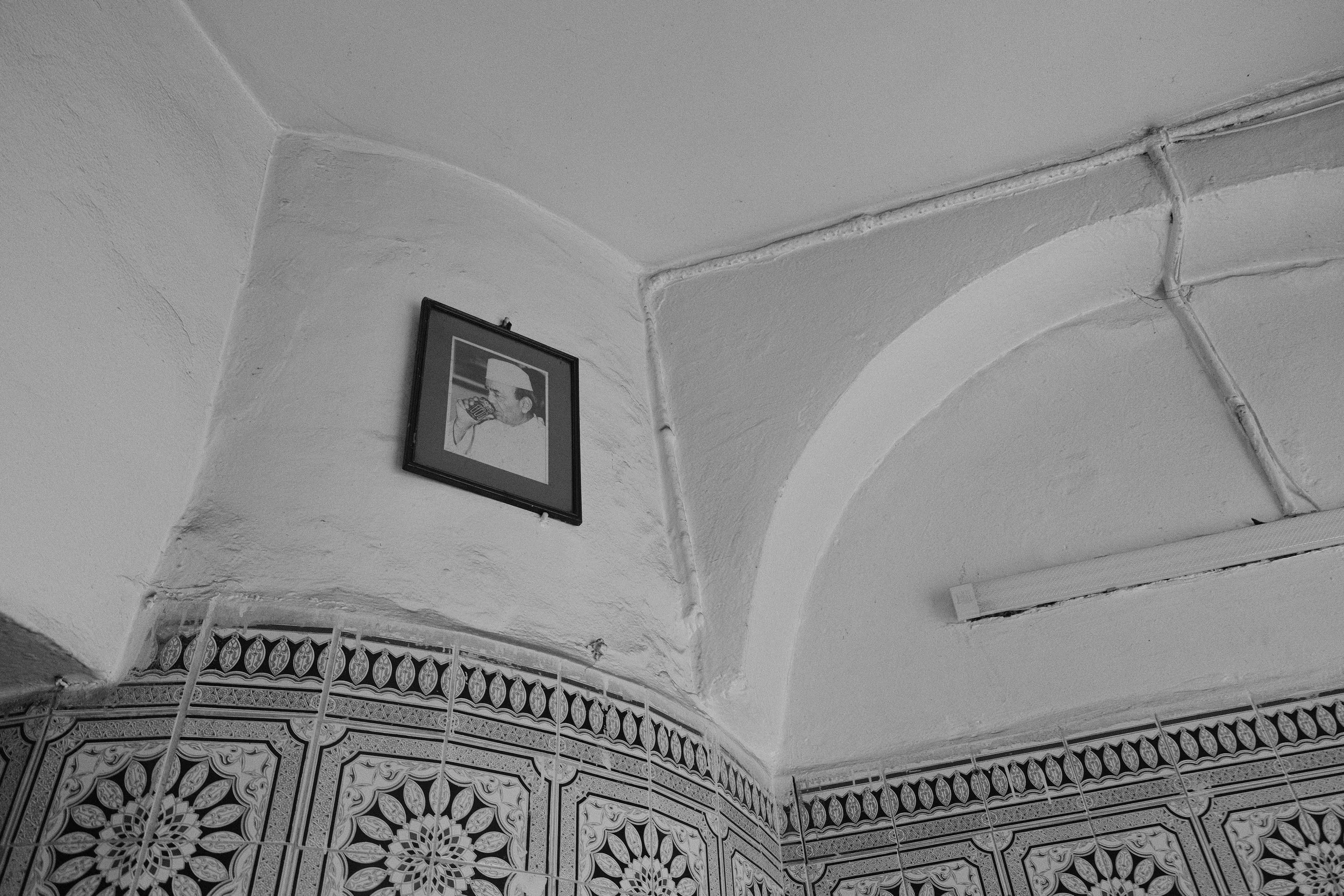 A framed photo of former King Hassan II drinking tea hangs on the wall.