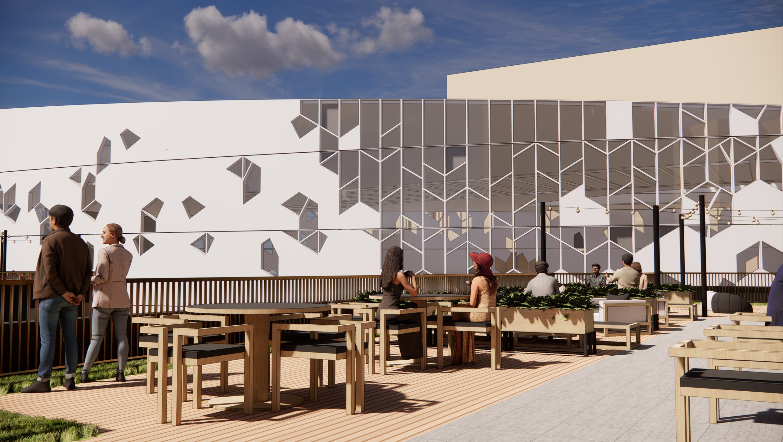 People sitting and standing on an outdoor patio with wooden furniture, overlooking a modern building with an irregular white facade and glass windows, under a partly cloudy sky.