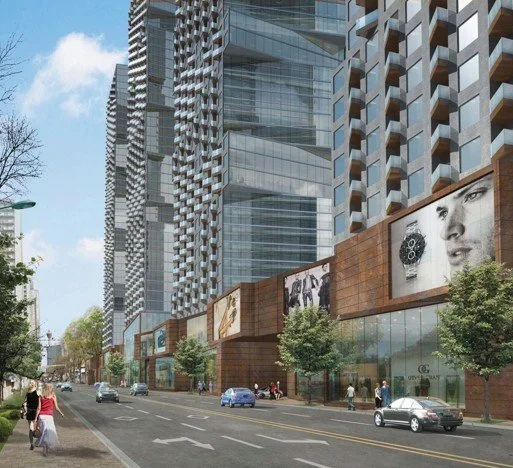 City street scene with modern high-rise buildings, retail shops, pedestrians, and parked cars.