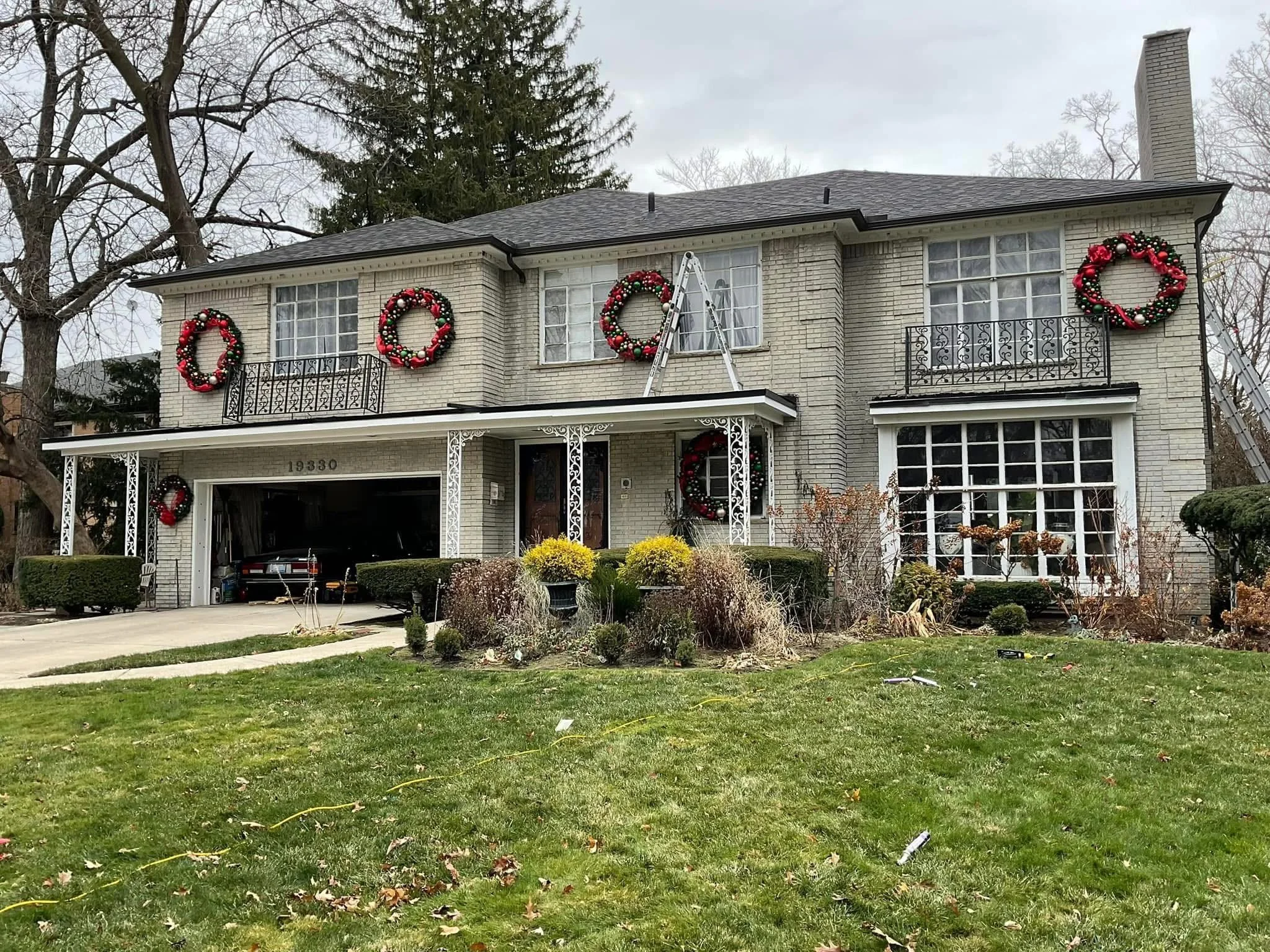 A two-story house decorated with Christmas wreaths on the exterior walls and porch. beautiful mansion with dads seamless gutters installed 6' gutters in Farmington hills michigan
